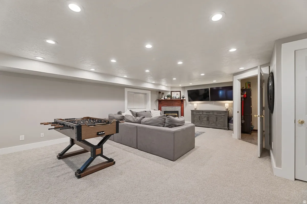 Spacious entertainment area featuring recessed lighting, light-toned carpeting, and a built-in fireplace with a red-toned mantel