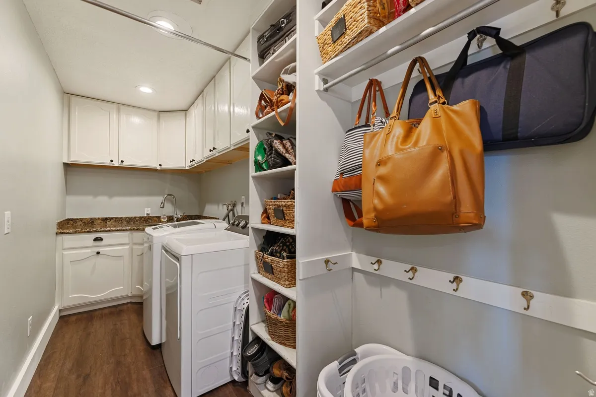 Dedicated laundry room featuring white cabinetry, stone-finish countertops, and wood-finish flooring