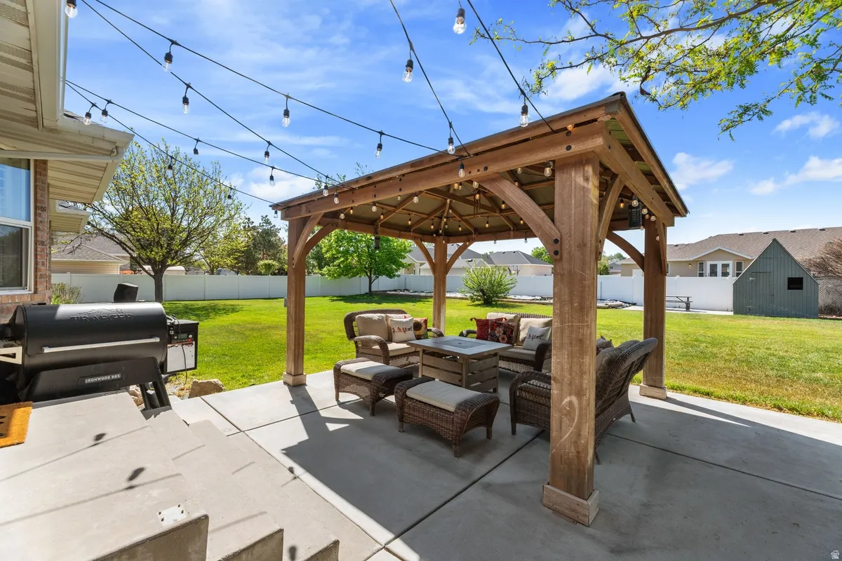 Spacious concrete patio featuring a wood pergola, string lighting, and extensive green space