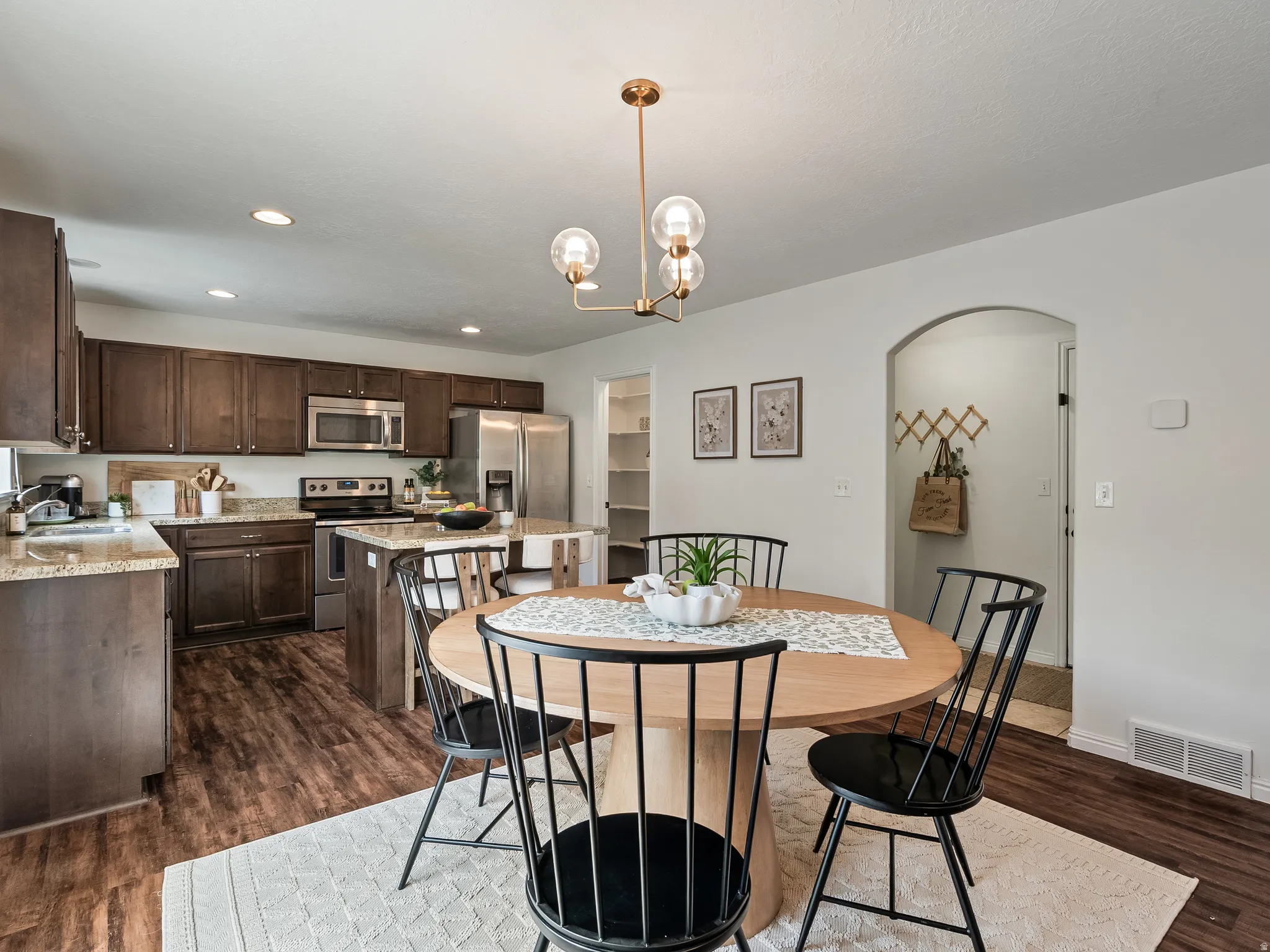 Bright dining area featuring a contemporary chandelier and wood-finish flooring