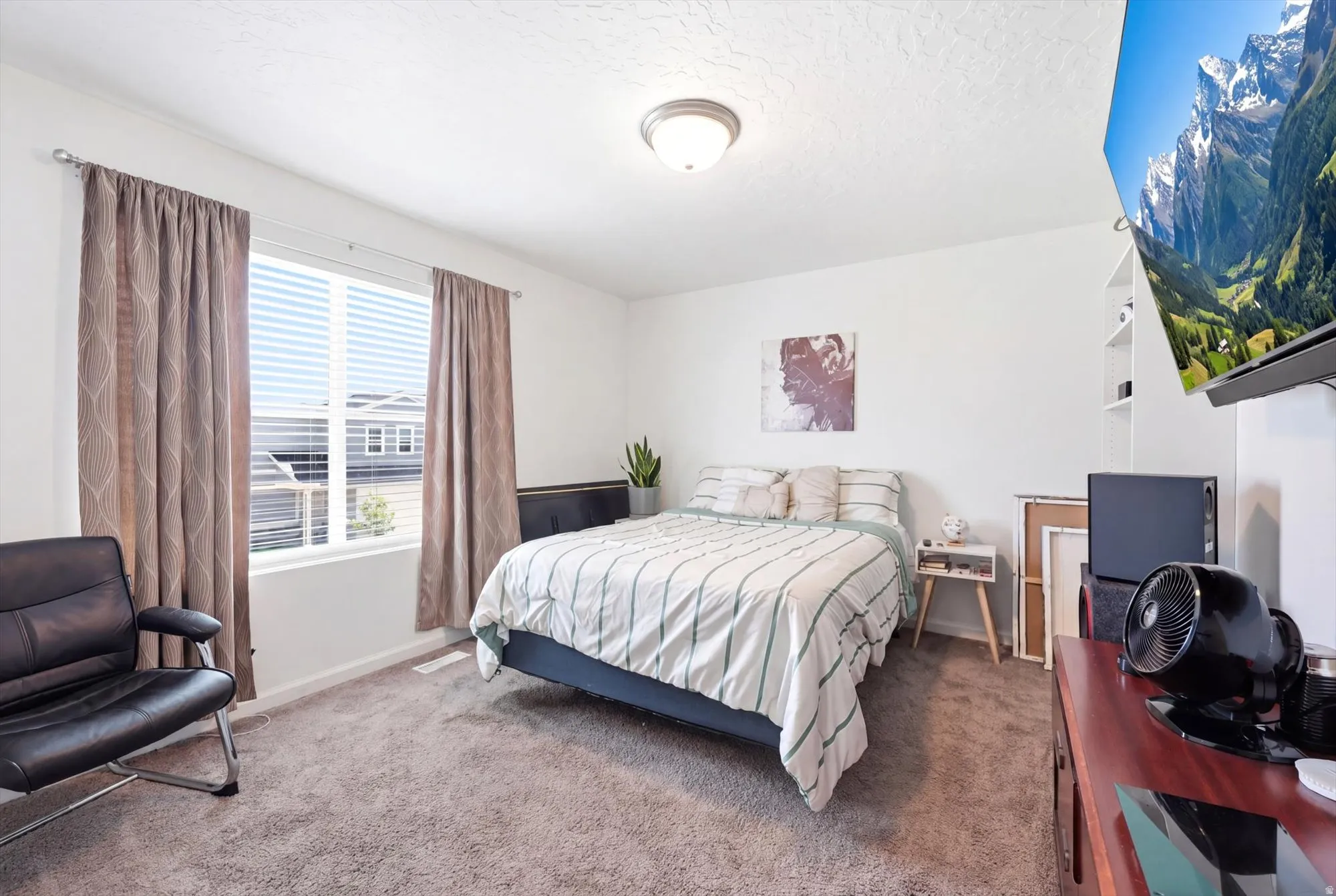 Carpeted room featuring a large window with blinds, white walls, and a ceiling-mounted light fixture