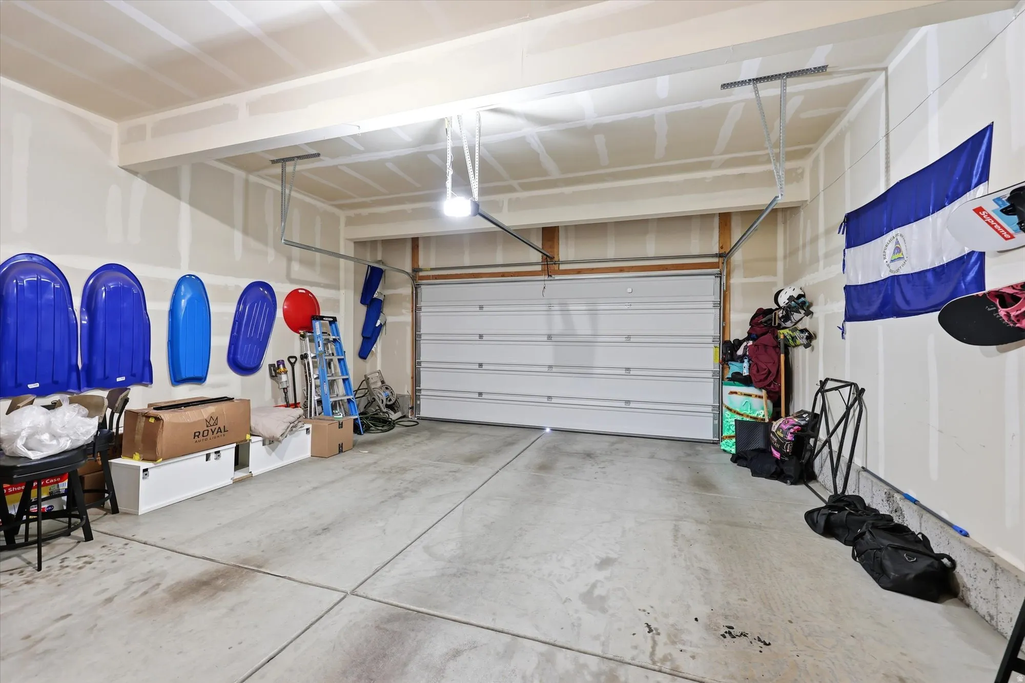 Garage featuring an overhead door, exposed ceiling joists, and concrete flooring