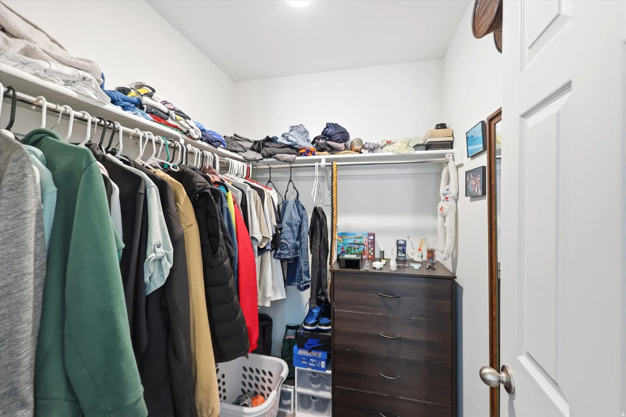 Walk-in closet featuring white walls, integrated shelving, and clothing rods