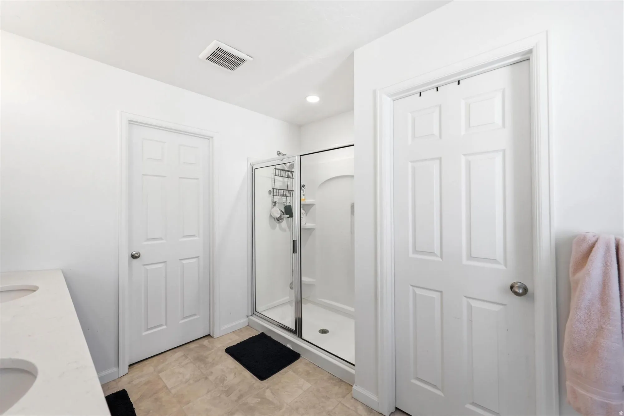 Bathroom featuring a glass-enclosed shower, dual basin vanity with integrated sinks, and neutral tone flooring