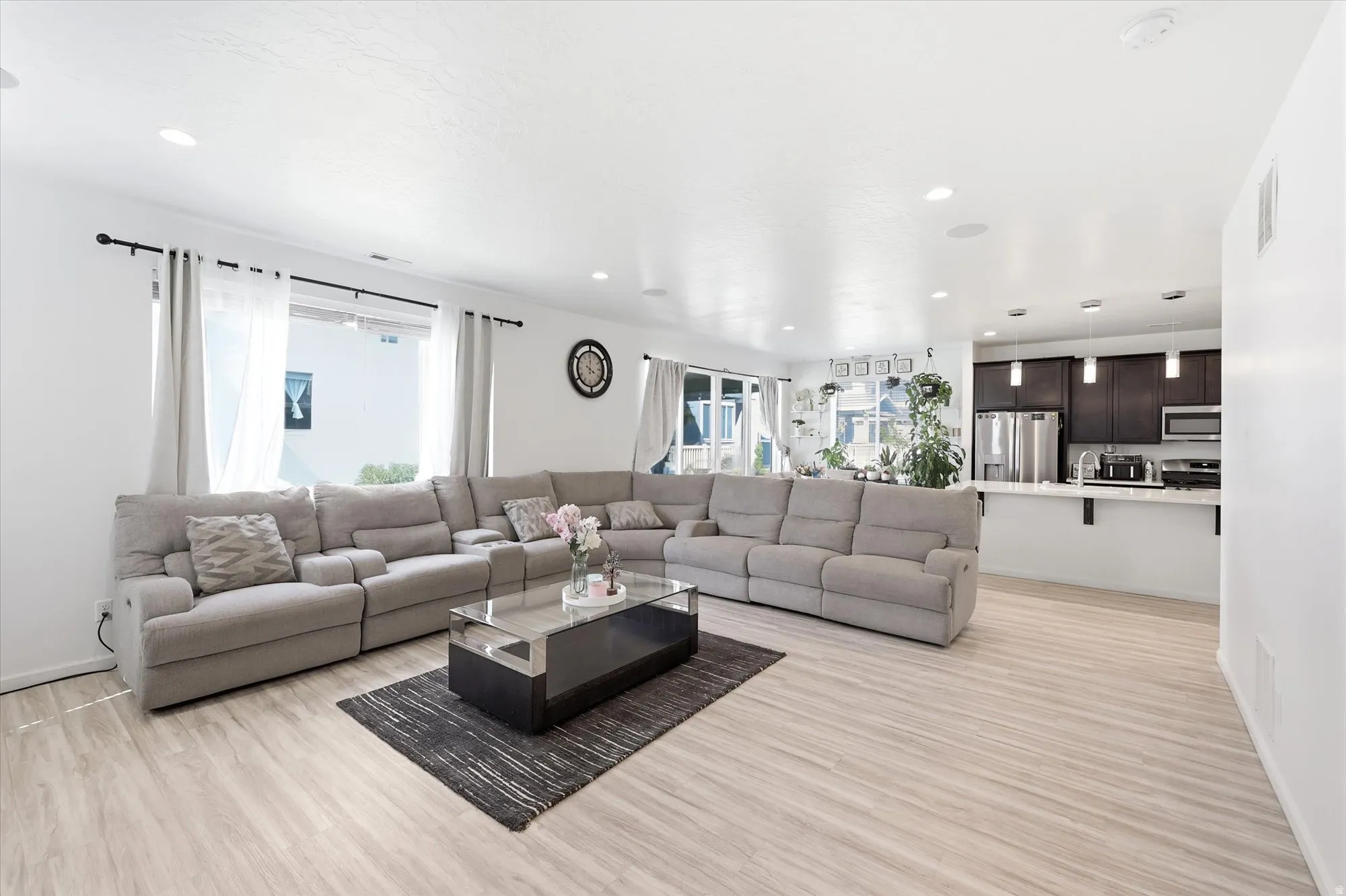Open-concept living space featuring light wood-finish flooring, recessed lighting, and a kitchen pass-through with pendant lighting