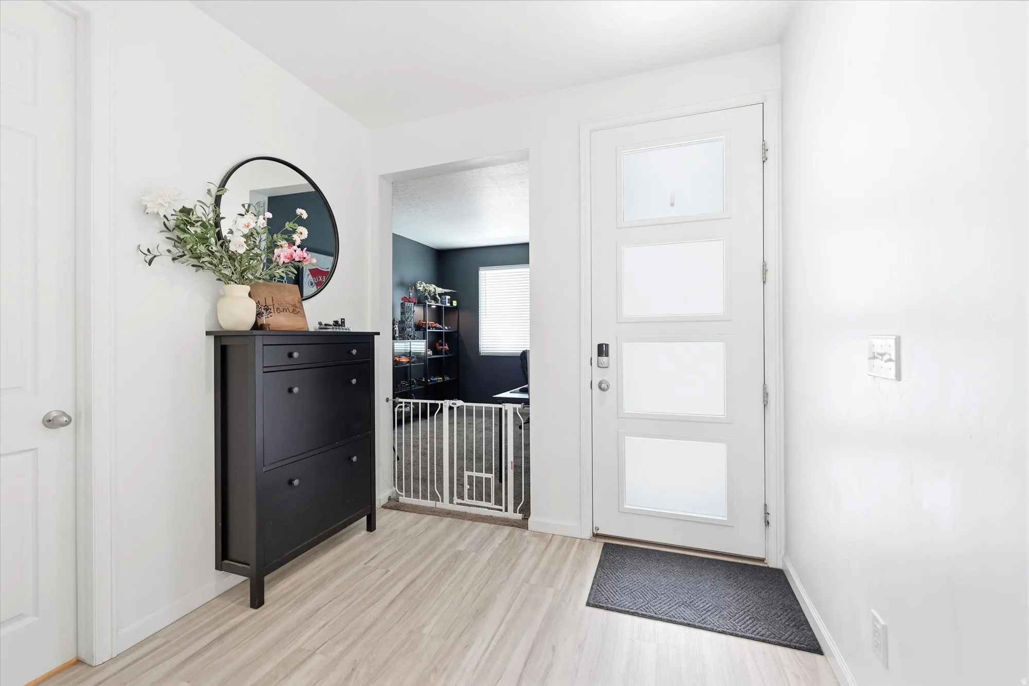 Front entry featuring a modern white door with frosted glass panels, light wood-finish flooring, and bright white walls