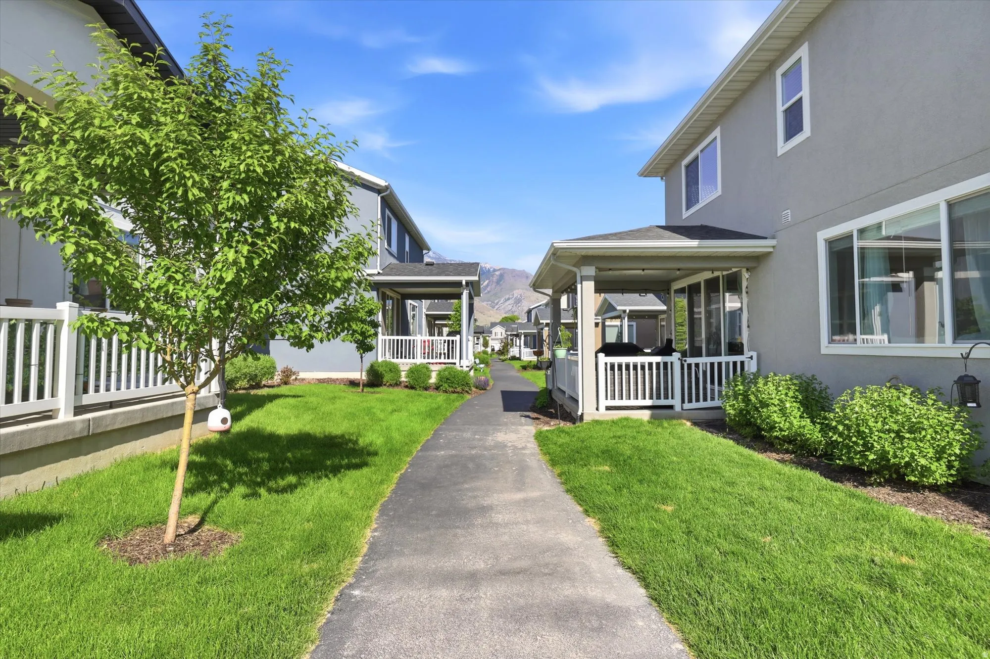 Rear exterior featuring a covered patio, white railing, and a paved pathway