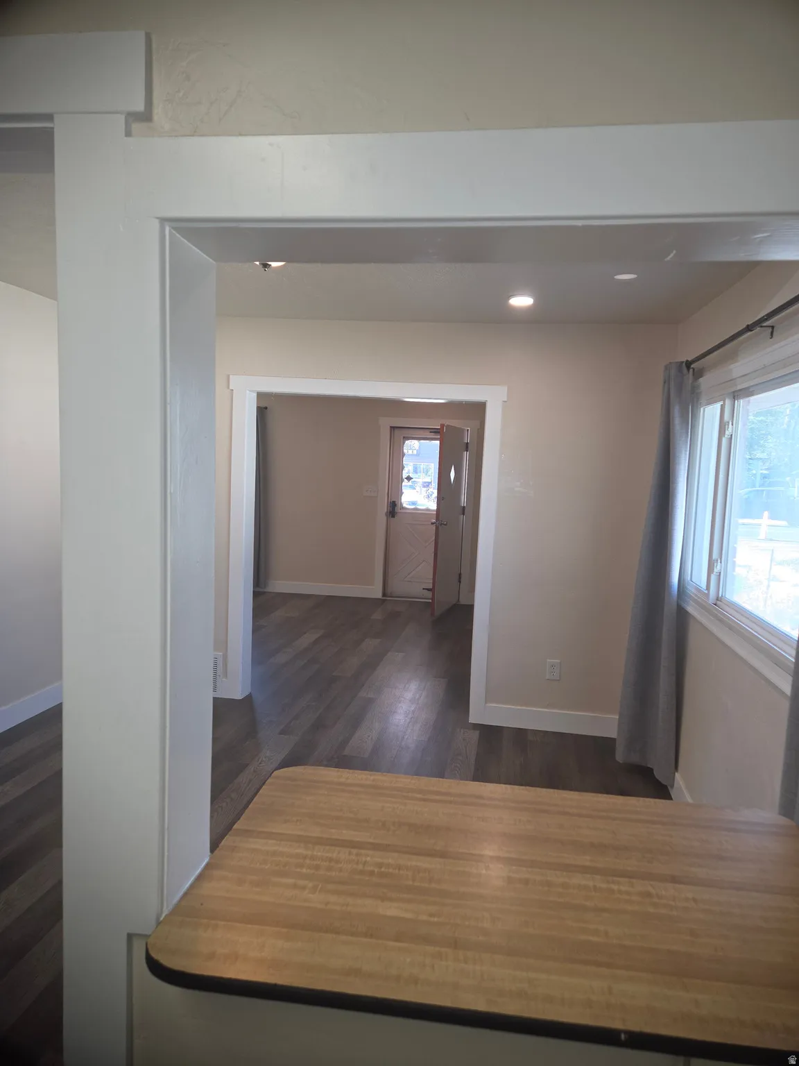 Interior architectural opening with white trim and recessed lighting, featuring wood-finish flooring and a light-toned countertop