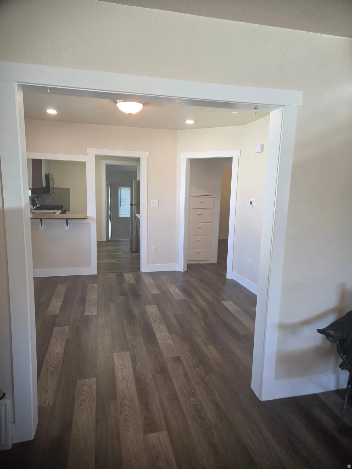 Open-concept living space with wood-finish flooring, recessed lighting, and a built-in breakfast bar