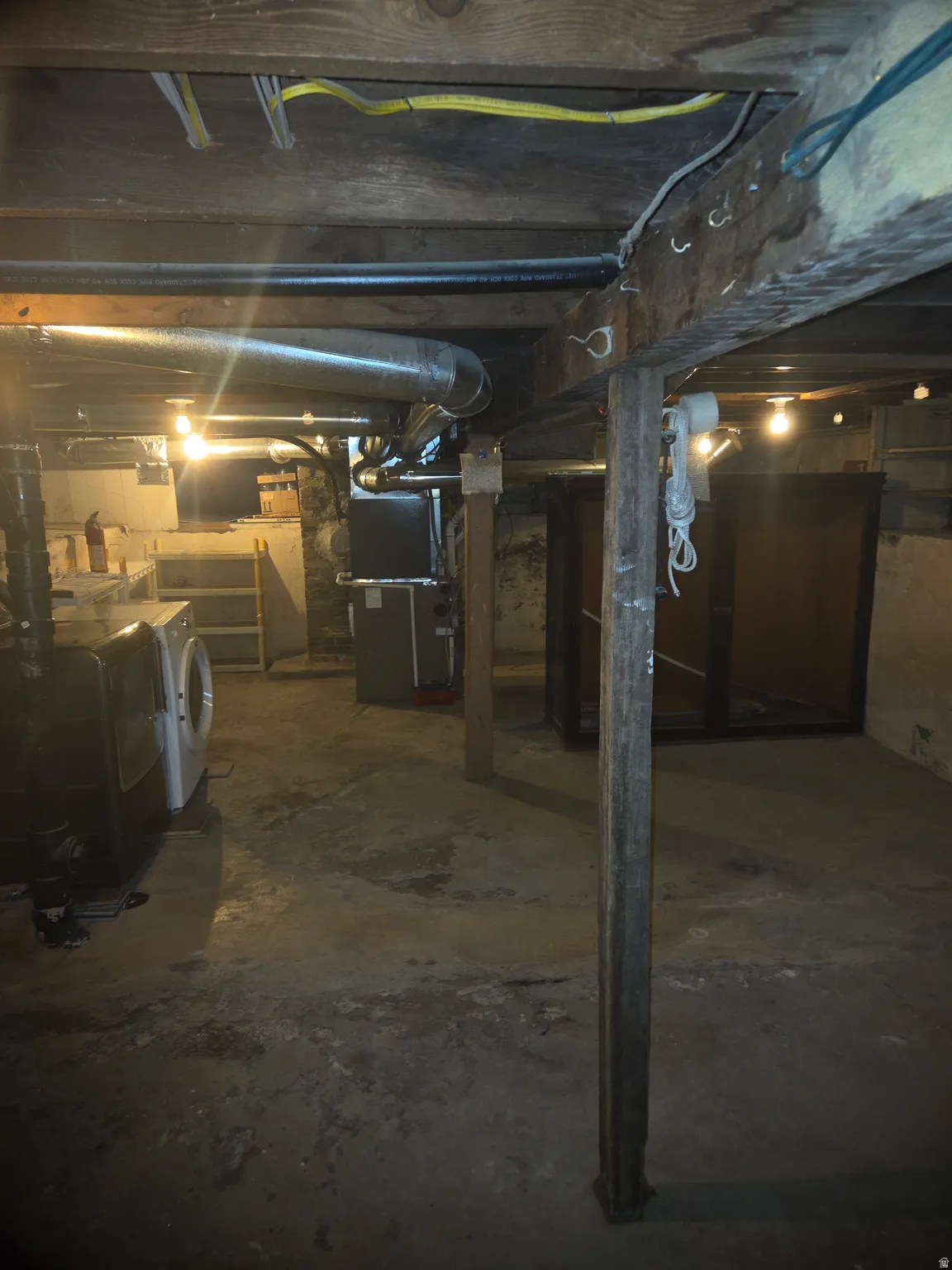 Unfinished basement with exposed wood joists and concrete flooring