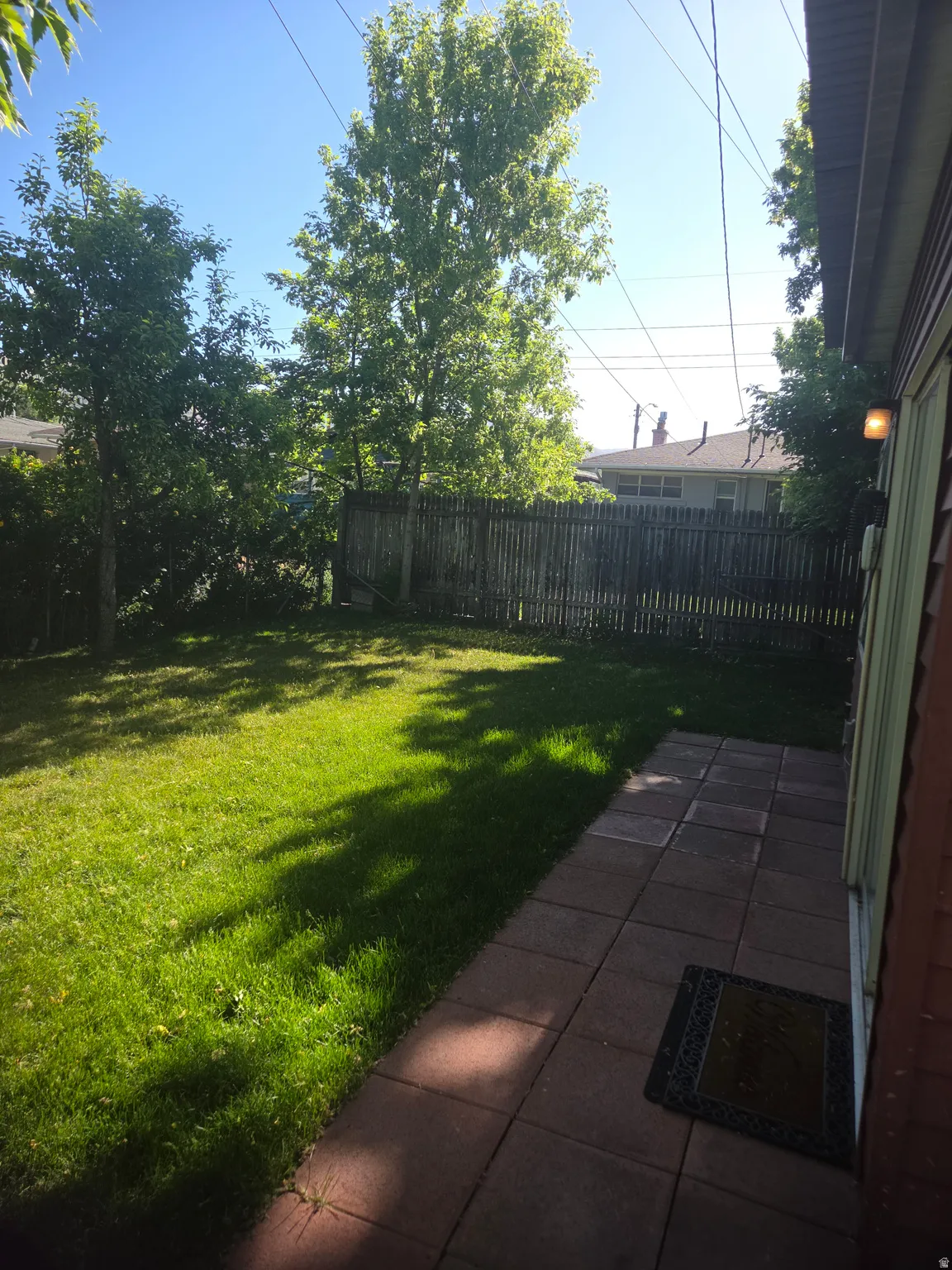 Expansive lawn area with mature trees and a wood-slat fence