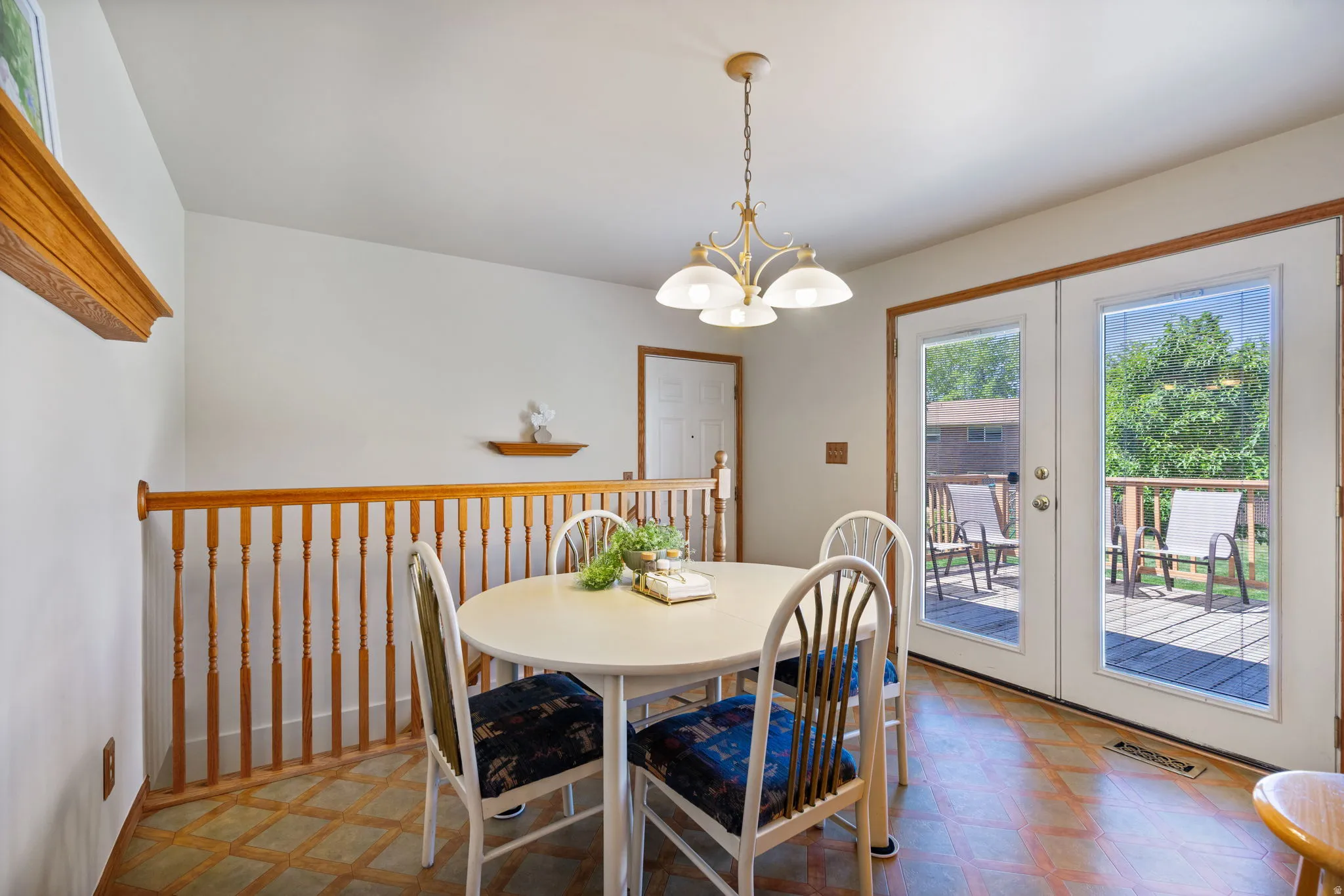 Dining area with a multi-light chandelier, double French doors, wood-finish flooring, and a wood railing