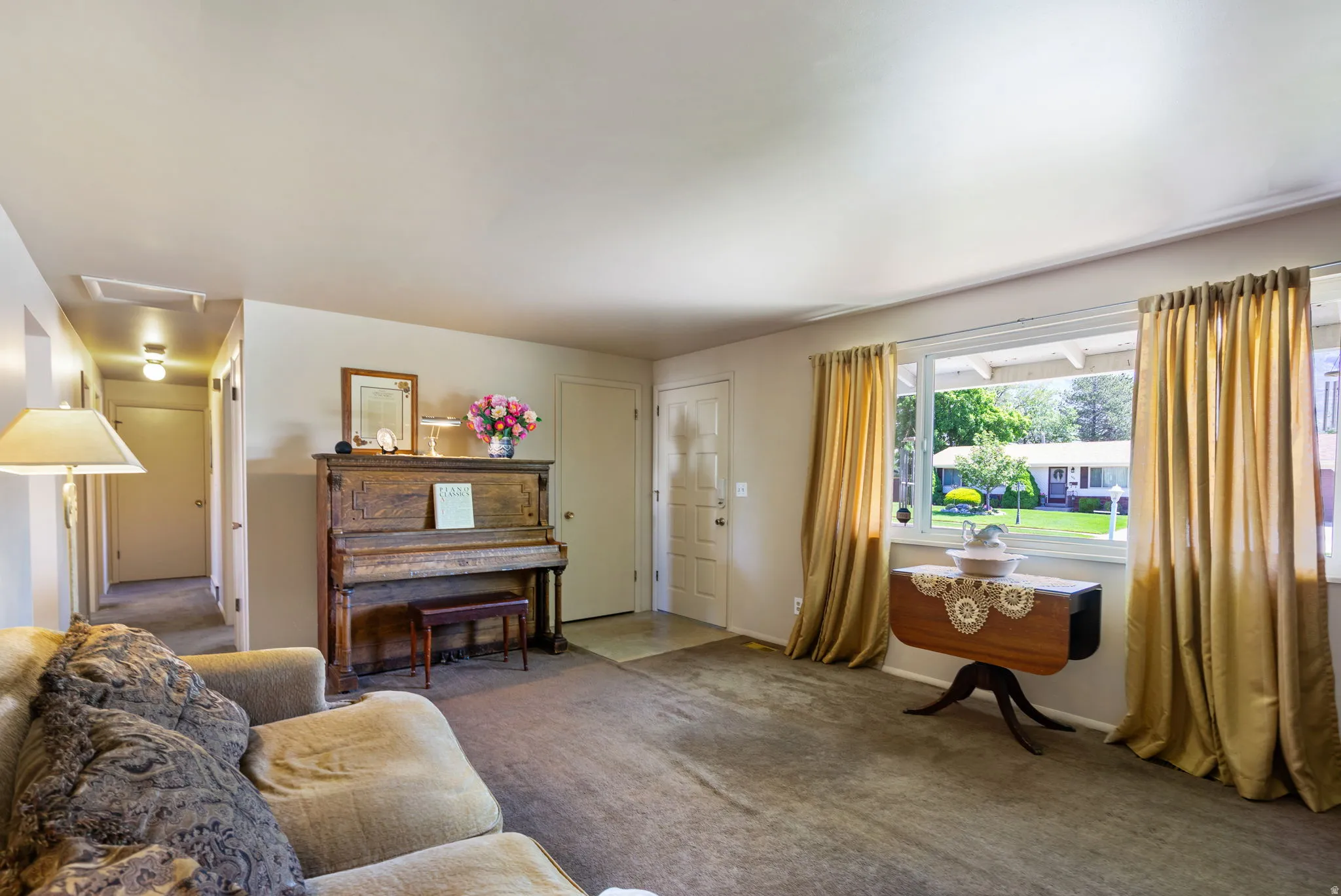 Spacious living area featuring neutral carpeting, light-toned wall paint, and a large picture window providing exterior visibility