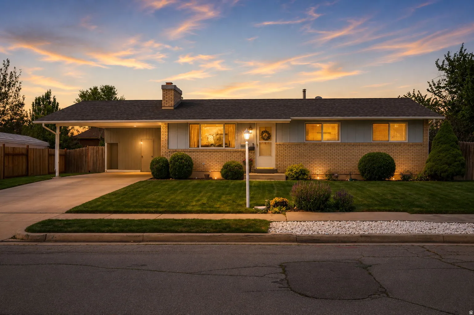 Ranch-style exterior featuring a carport, brick and siding facade, concrete driveway, and manicured landscaping with shrubbery and a lawn