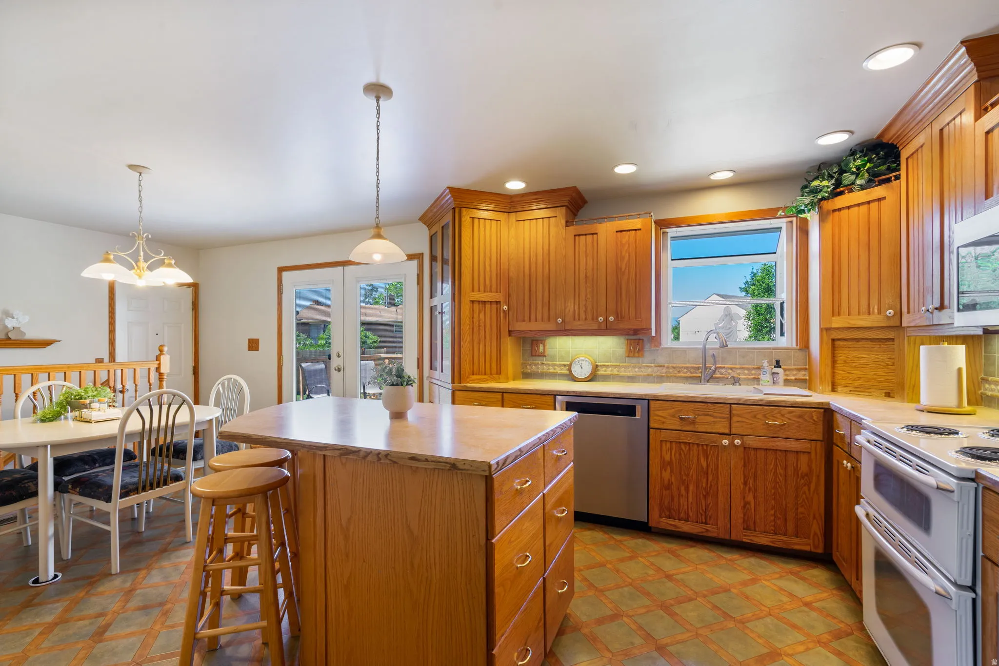 Kitchen featuring wood cabinetry, stone countertops, stainless steel dishwasher, double oven range, and tile flooring