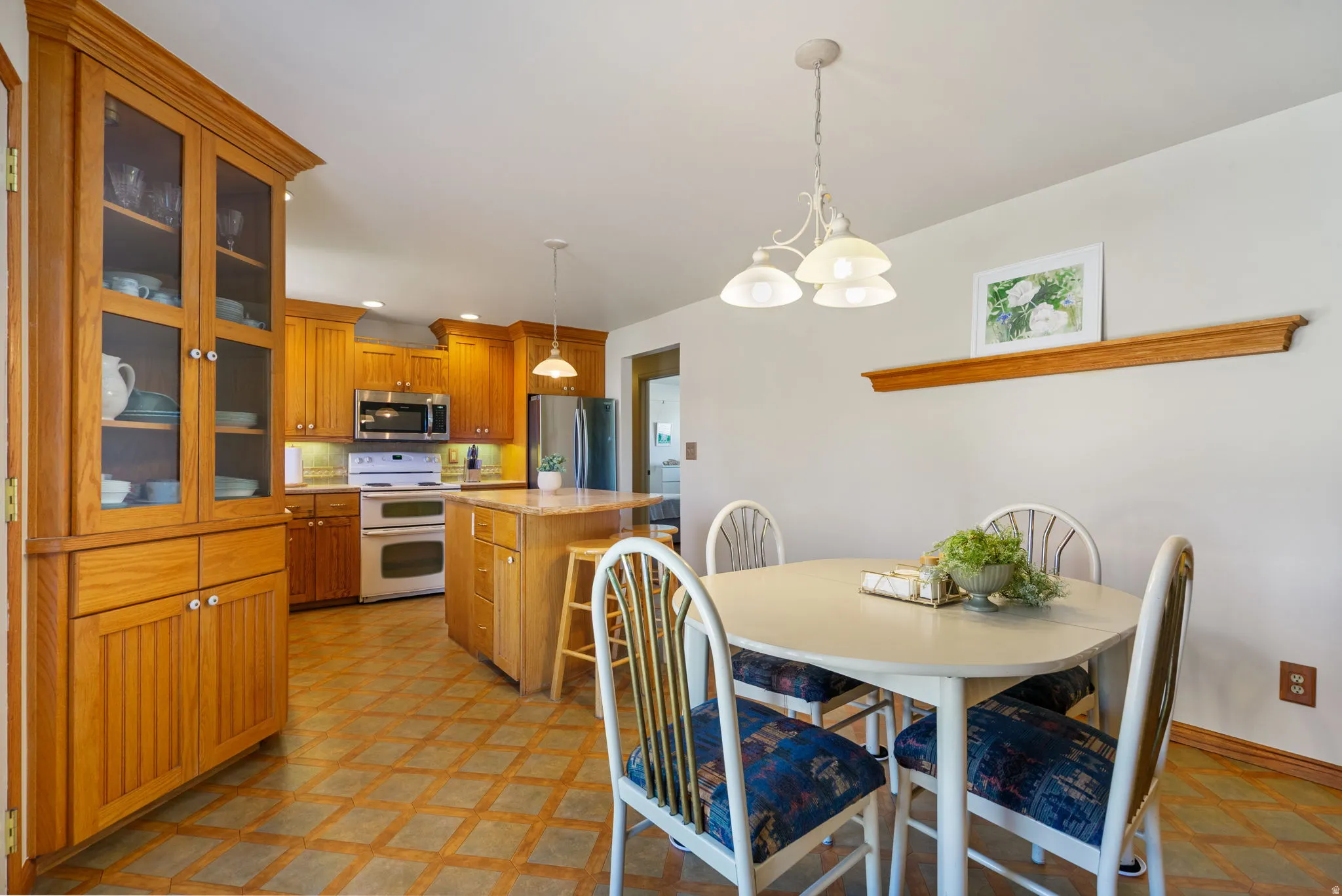 Kitchen featuring wood cabinetry, stainless steel appliances, a center island with seating, and geometric-patterned flooring