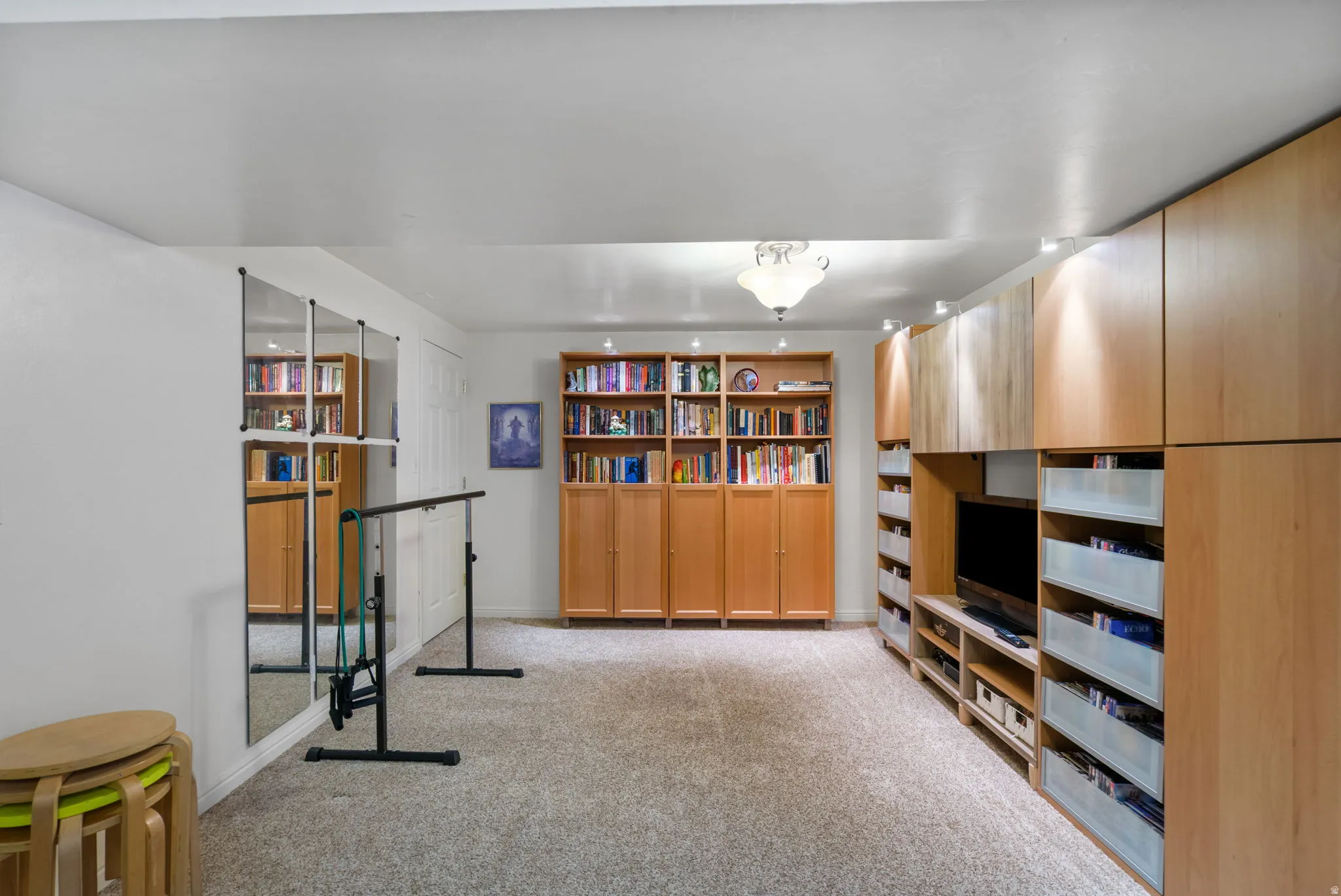 Flexible space featuring extensive built-in cabinetry, wall-mounted mirrors, and carpeted flooring