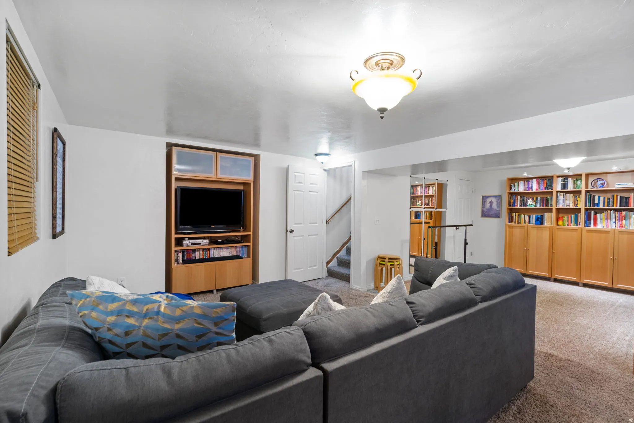 Entertainment area featuring built-in cabinetry, recessed lighting, and neutral-tone carpeting