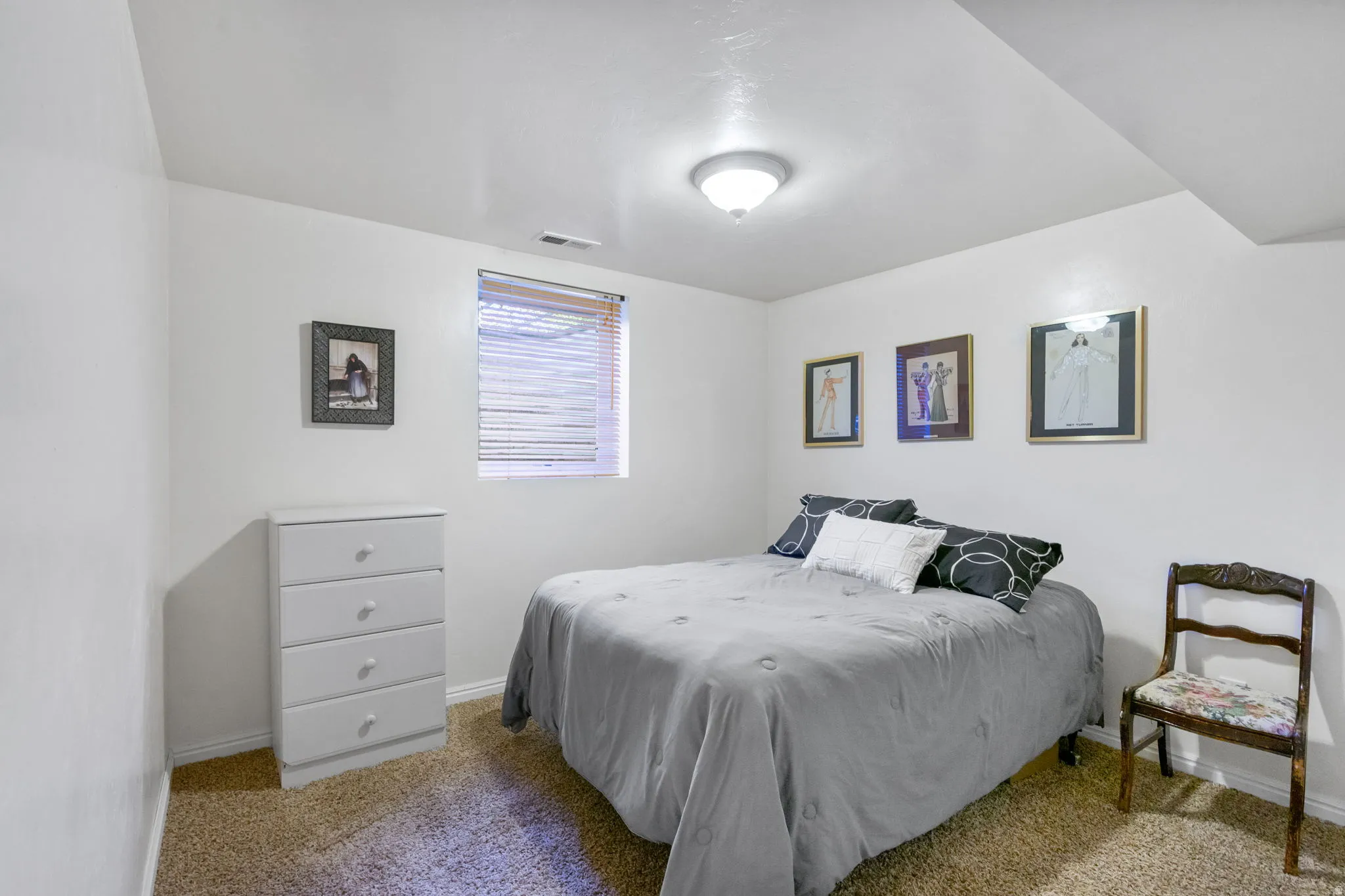 Carpeted room featuring a single window with blinds, white walls, and a ceiling-mounted light fixture