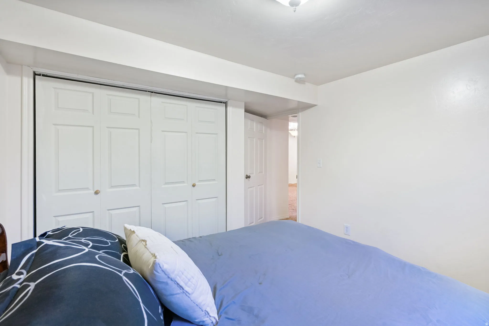 Bedroom featuring white walls and a large bi-fold closet