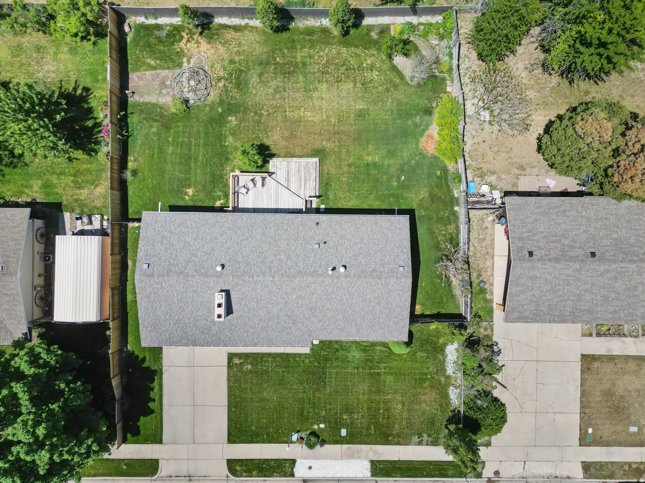 Expansive backyard featuring a wood deck, green lawn, and surrounding fencing