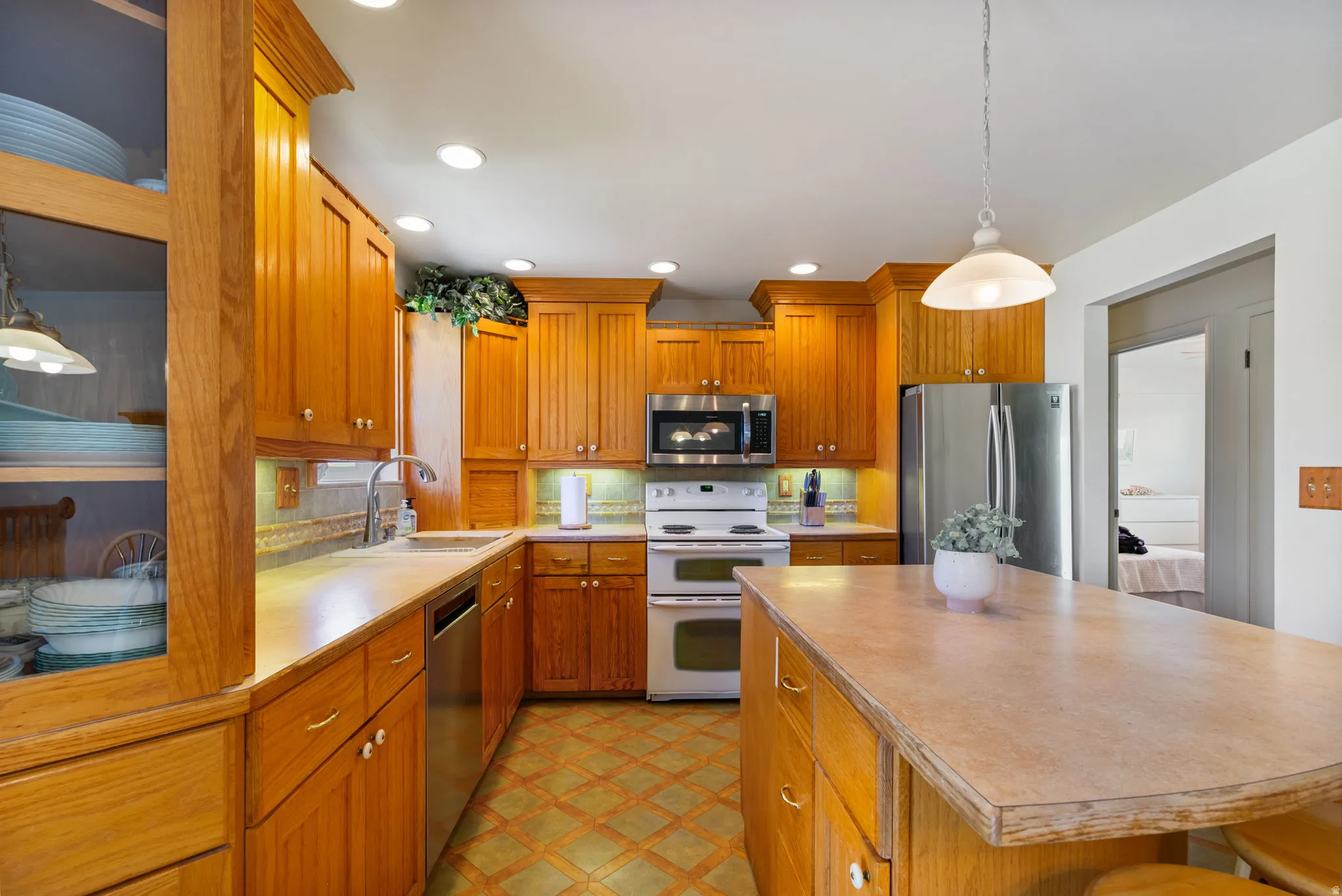 Kitchen featuring wood cabinetry, stainless steel appliances, a center island with countertop seating, recessed lighting, and patterned floor tile