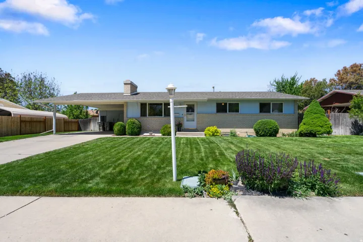 Ranch-style residence featuring a carport, a brick chimney, and a landscaped front yard