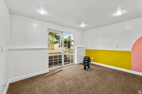 Room featuring brown carpet flooring, white walls with a yellow accent band, and recessed ceiling lighting