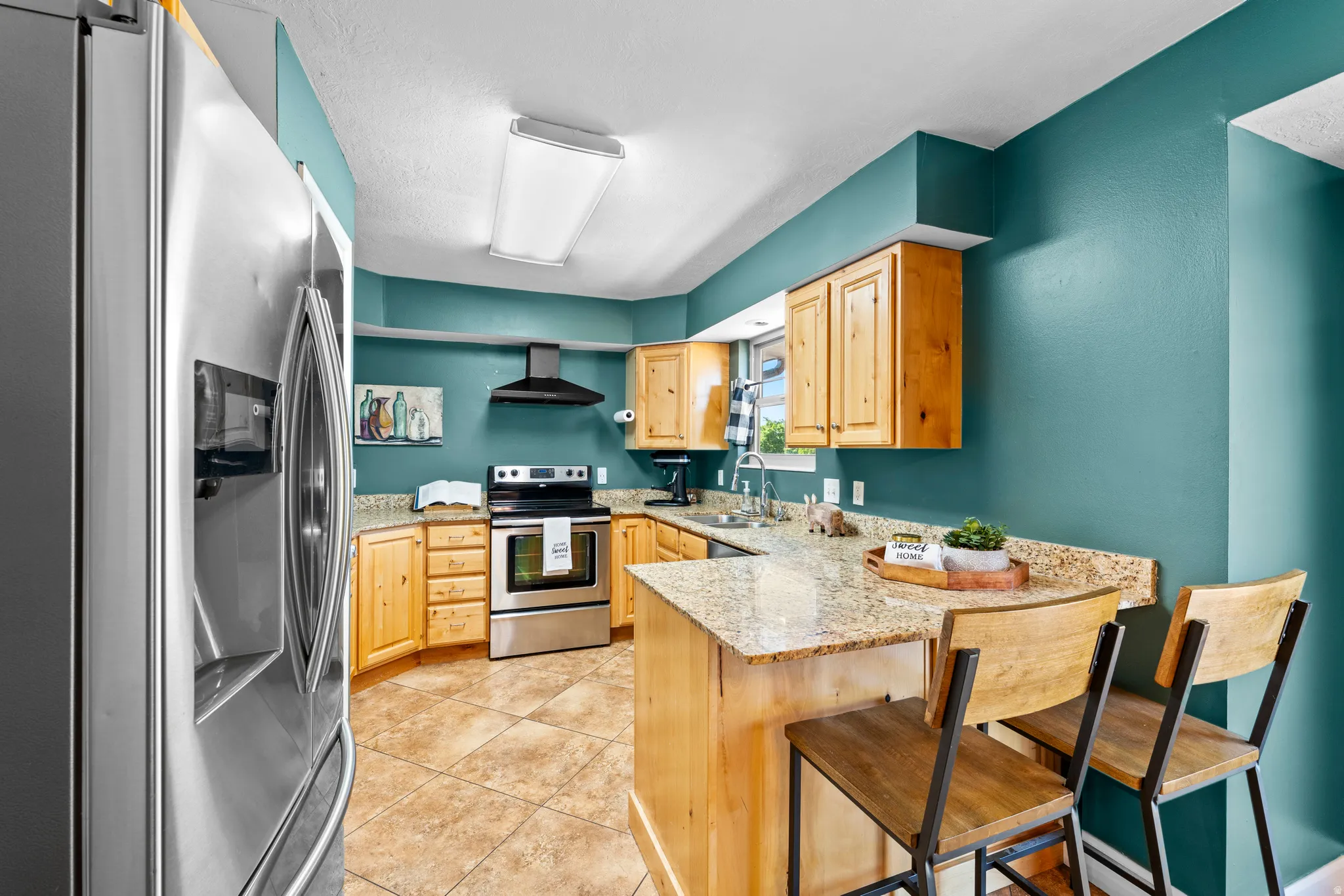 Kitchen featuring natural wood cabinetry, stainless steel appliances, granite-style countertops, an eat-at island, and tile flooring