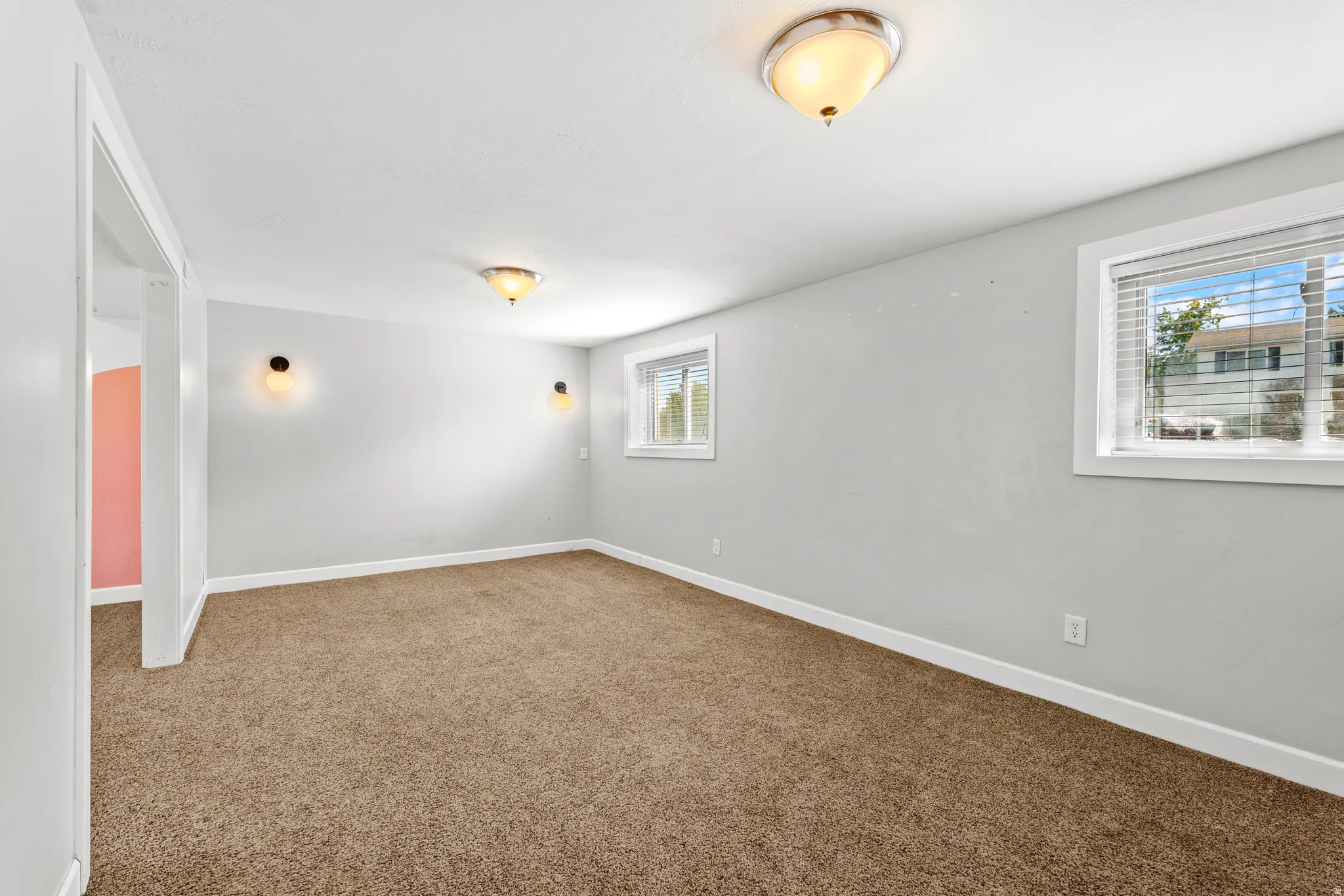 Spacious room featuring neutral carpeting, light gray walls, and white trim
