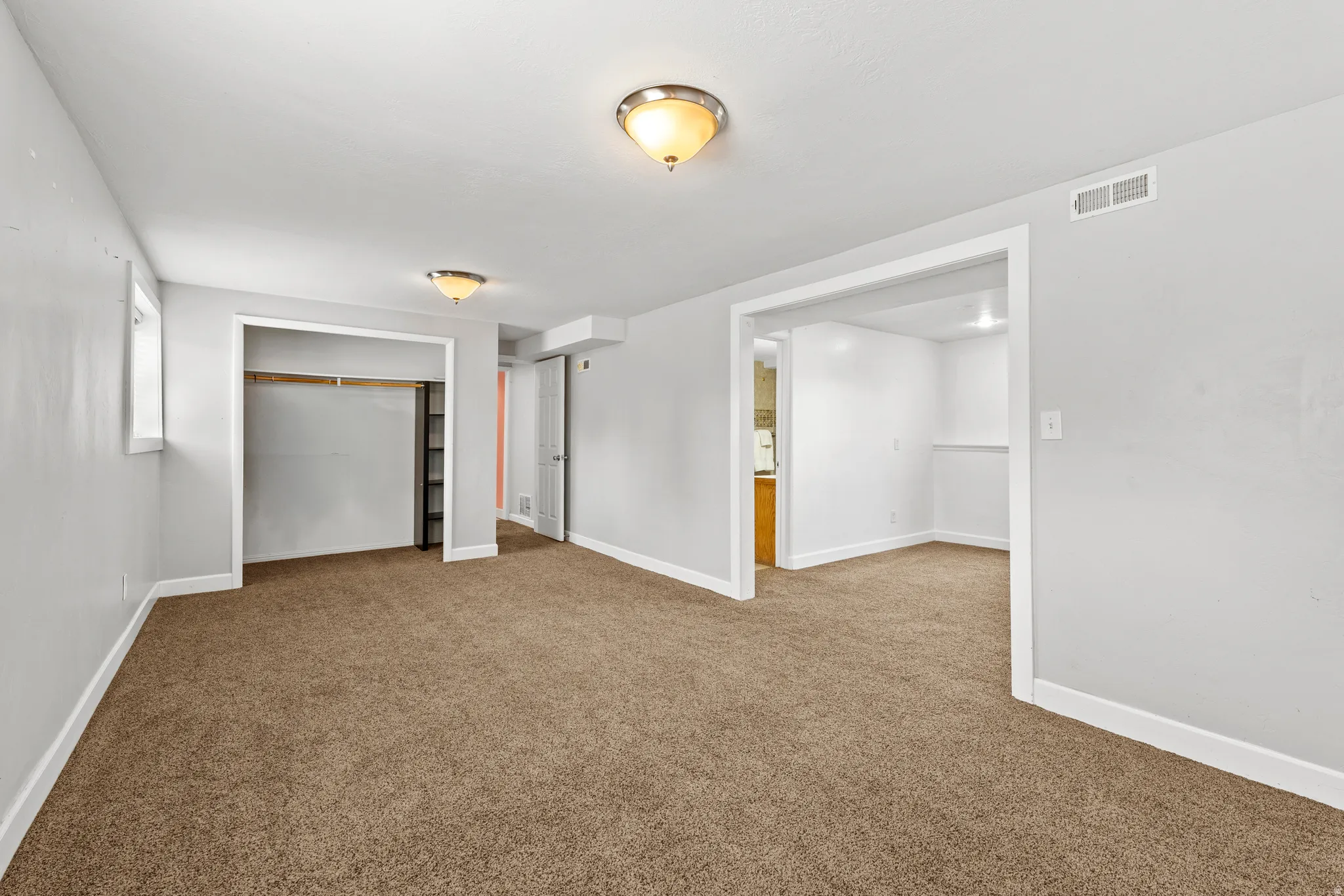 Spacious room featuring neutral carpeting and light gray wall tones