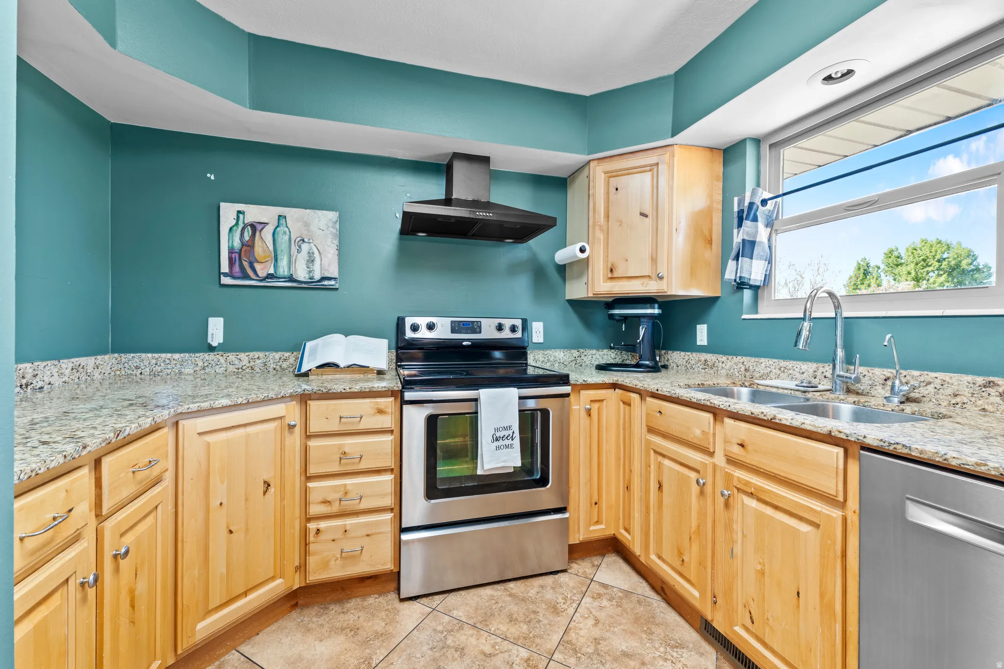 Kitchen featuring light wood cabinetry, granite-style countertops, stainless steel appliances, a double basin sink, and tile flooring