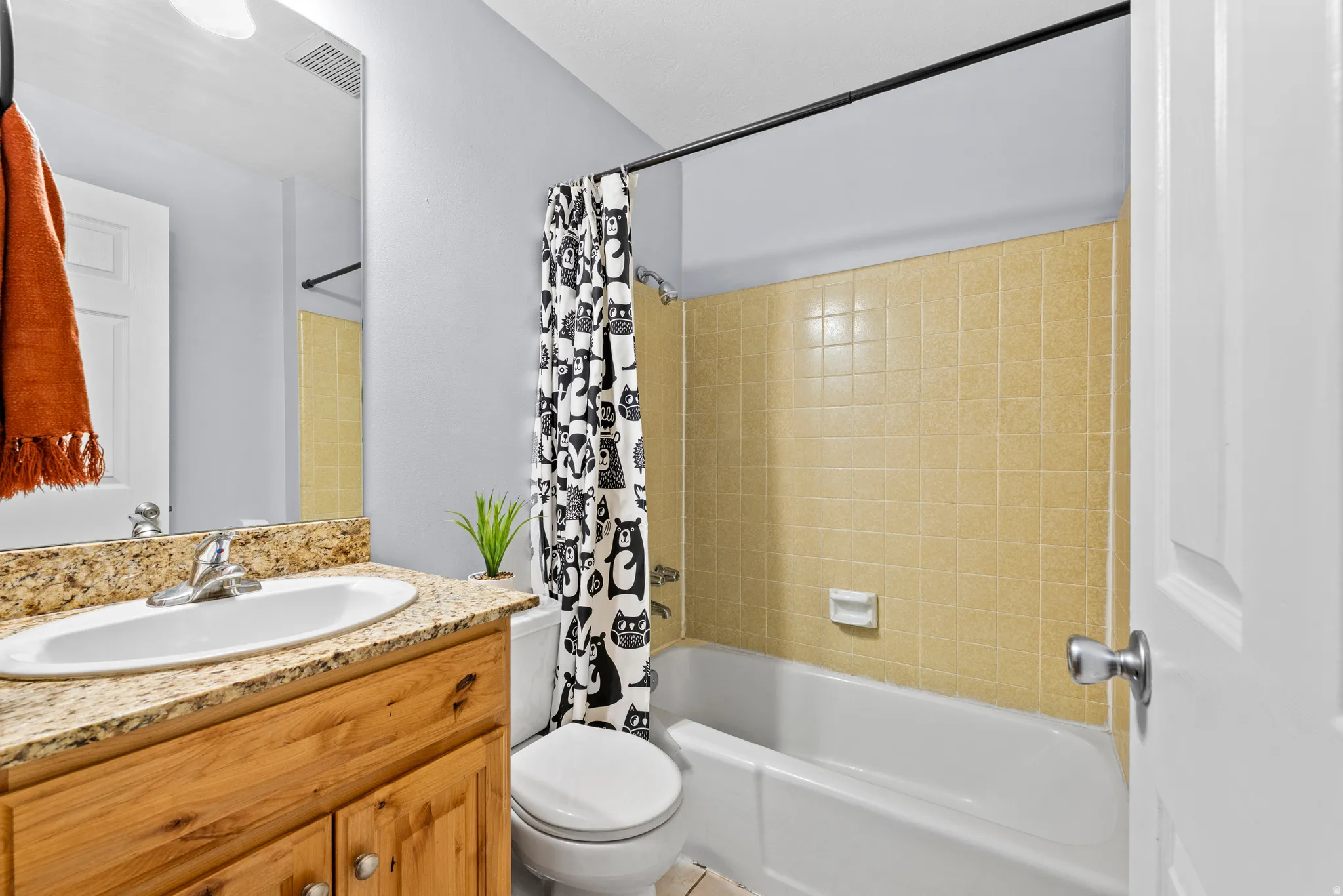 Bathroom featuring a wood-finish vanity with a granite-style countertop, undermount sink, and chrome faucet