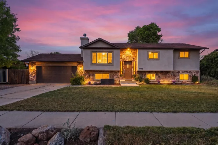 Split-level residence featuring a stone and stucco facade, a two-car garage, and a concrete driveway