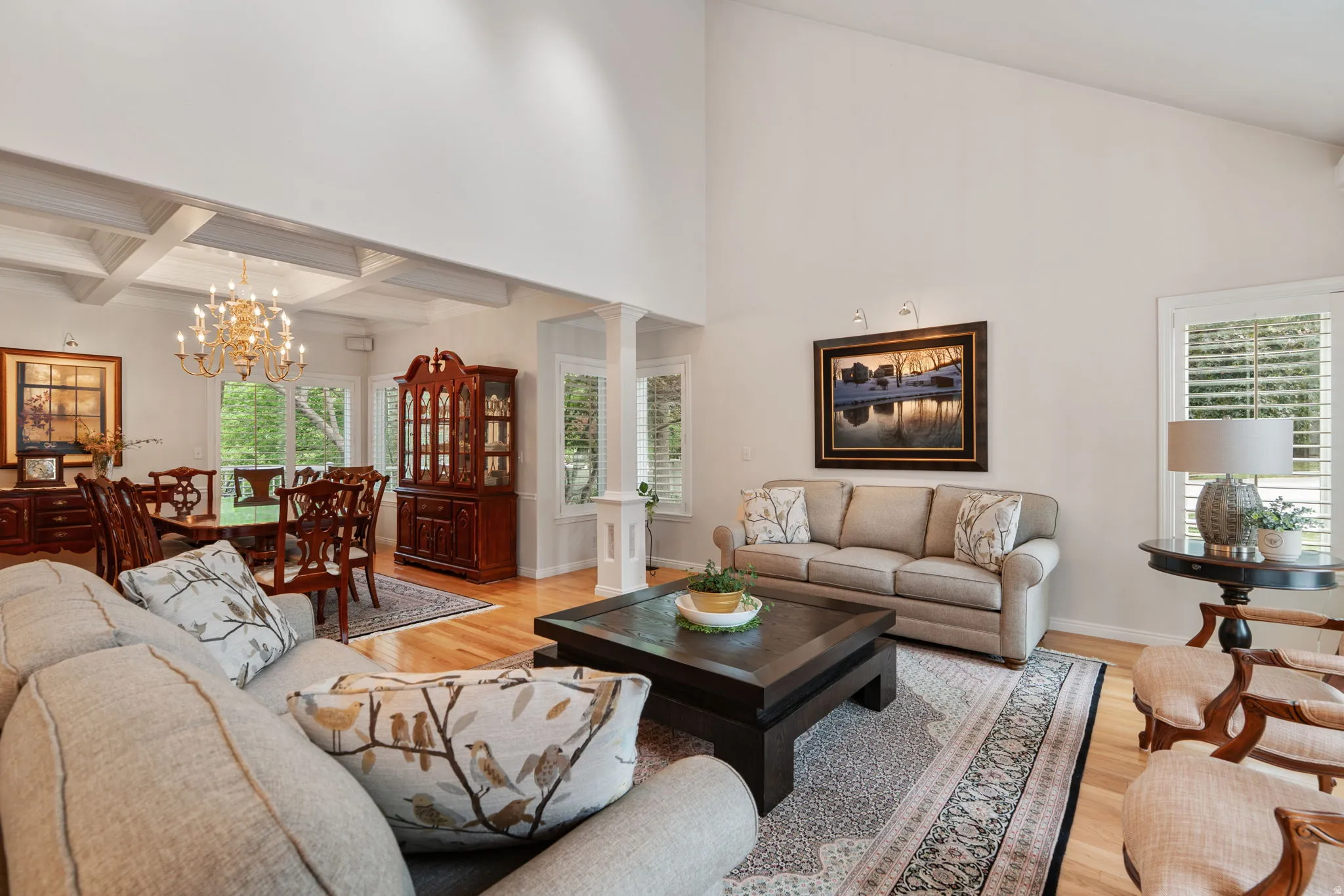 Vaulted ceilings define this living space, featuring wood-finish flooring and white plantation shutters