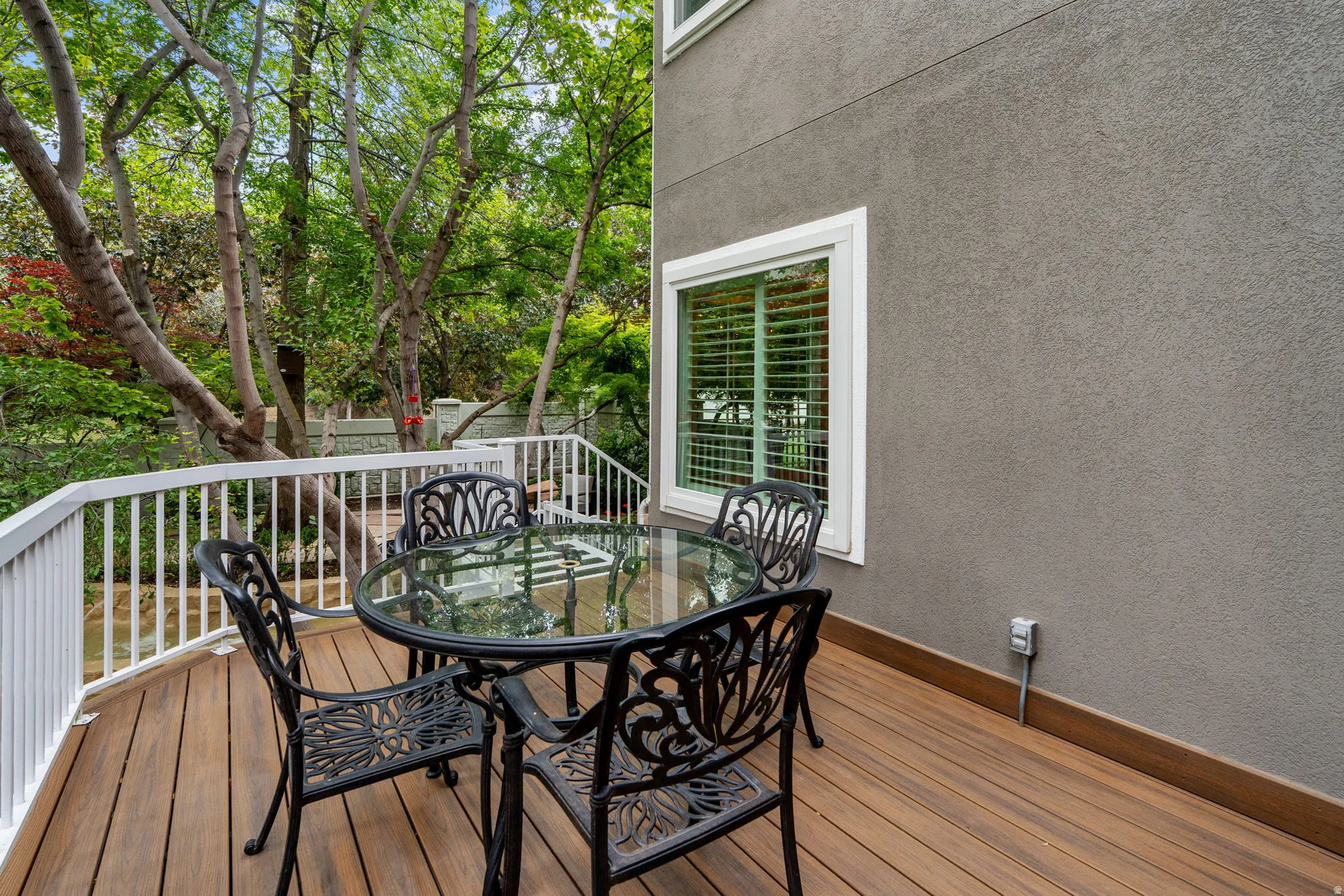 Outdoor deck located off kitchen featuring Trex flooring, abundance of trees and accesses the patio