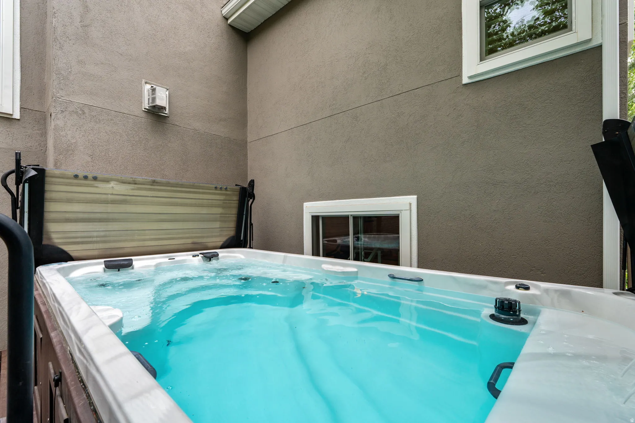 Arctic brand salt water outdoor swim spa with steps, set against a textured stucco exterior