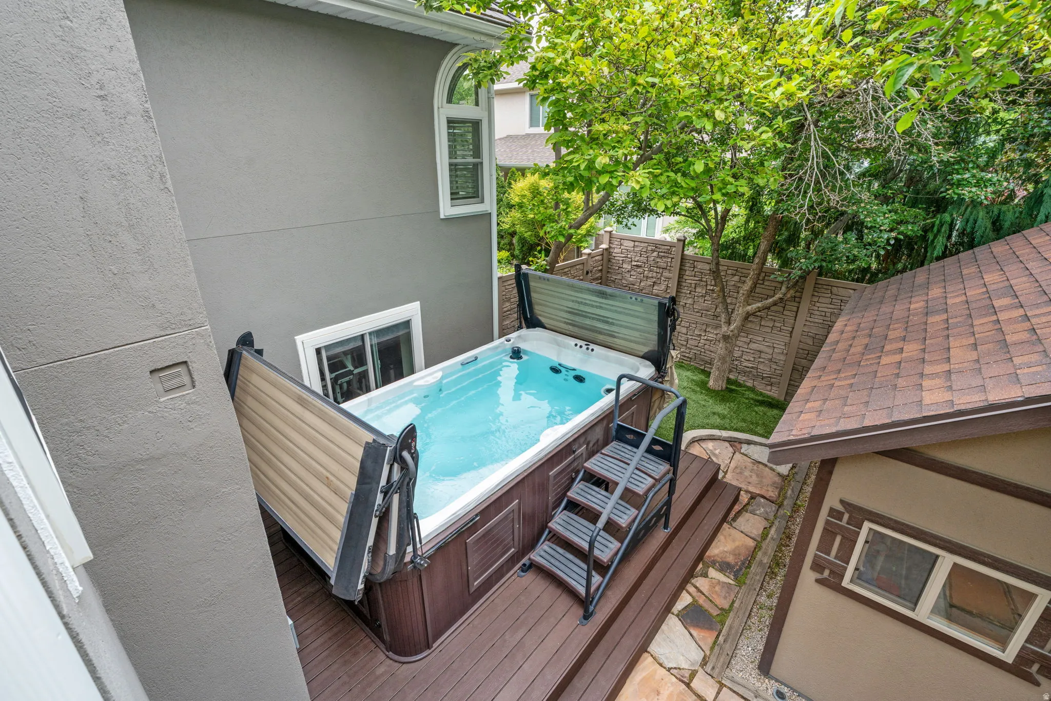 Arctic brand salt water swim spa with dark wood-finish paneling and a hydraulic lift protective cover, set on Trex deck