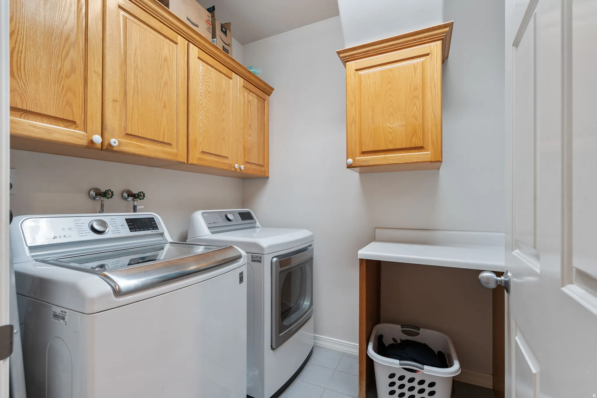 Laundry area featuring ample wood cabinetry, a utility sink connection, and a built-in folding counter