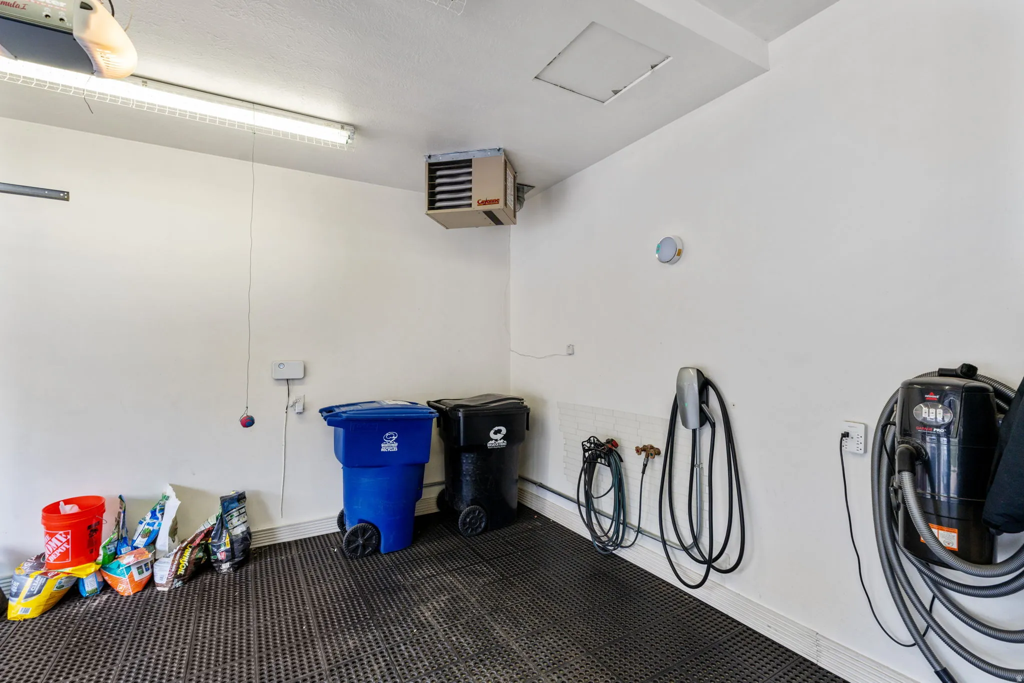Expansive heated garage space with epoxy floors covered with rubber tiles, EV charging station and wall vacuum