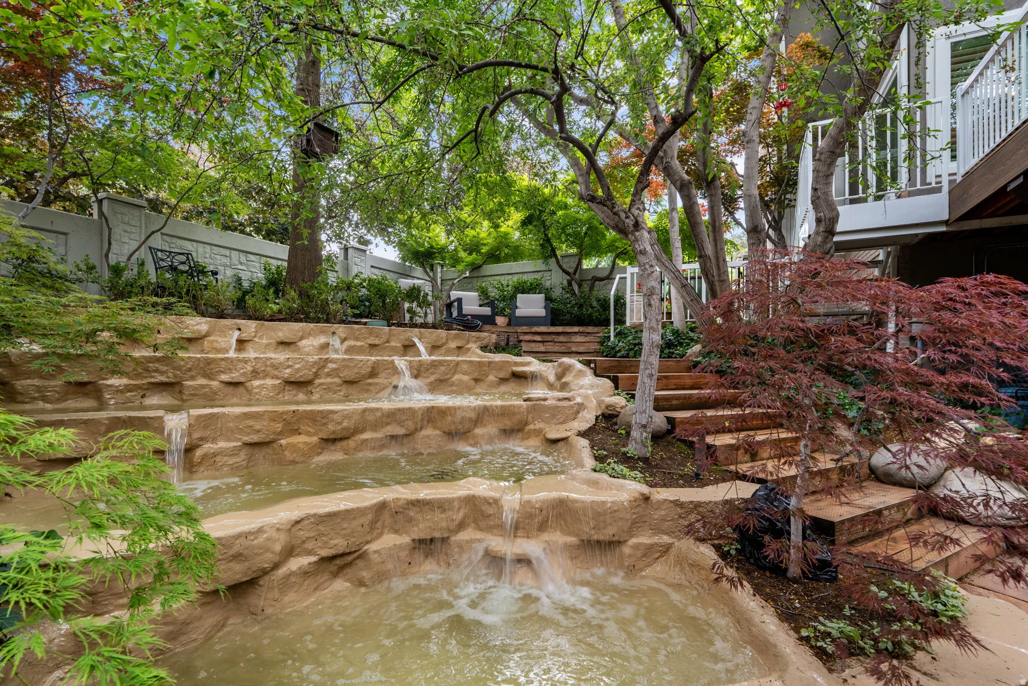 Grand multi-tiered water feature with mature trees and outdoor lighting