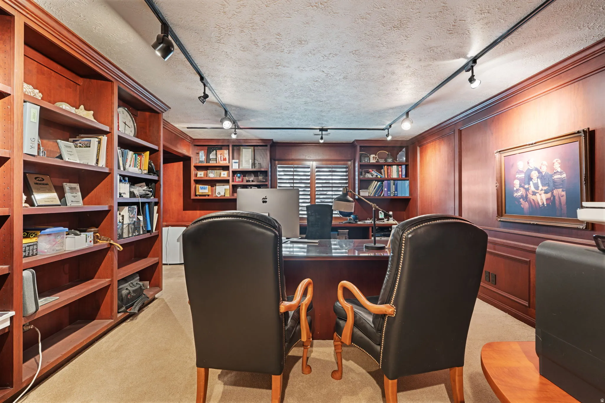 Library/office featuring extensive built-in cherry wood shelving, and paneled walls