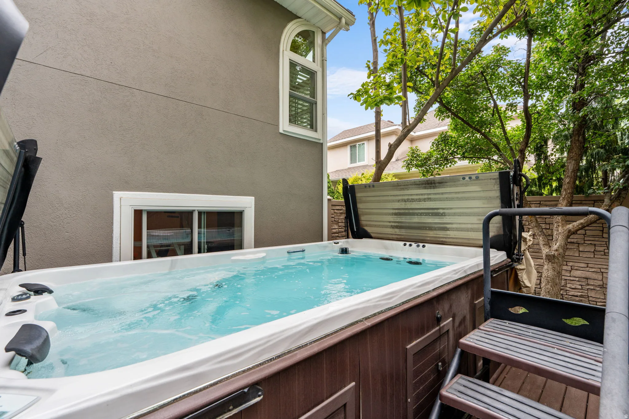 Arctic brand salt water swim spa featuring a wood-finish cabinet, hydraulic lift cover and integrated steps