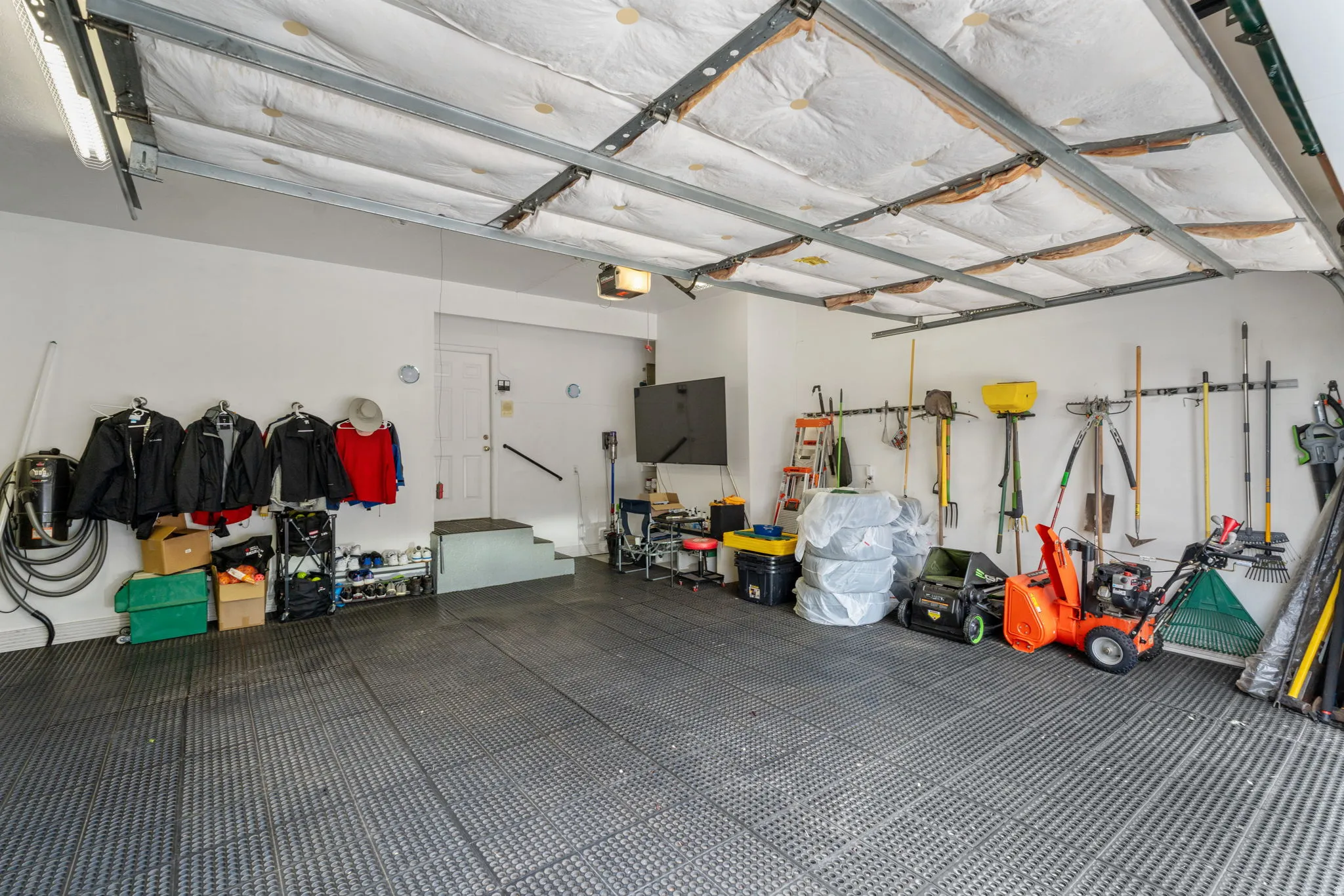 Expansive heated garage space with epoxy floors covered with rubber tiles, EV charging station and wall vacuum