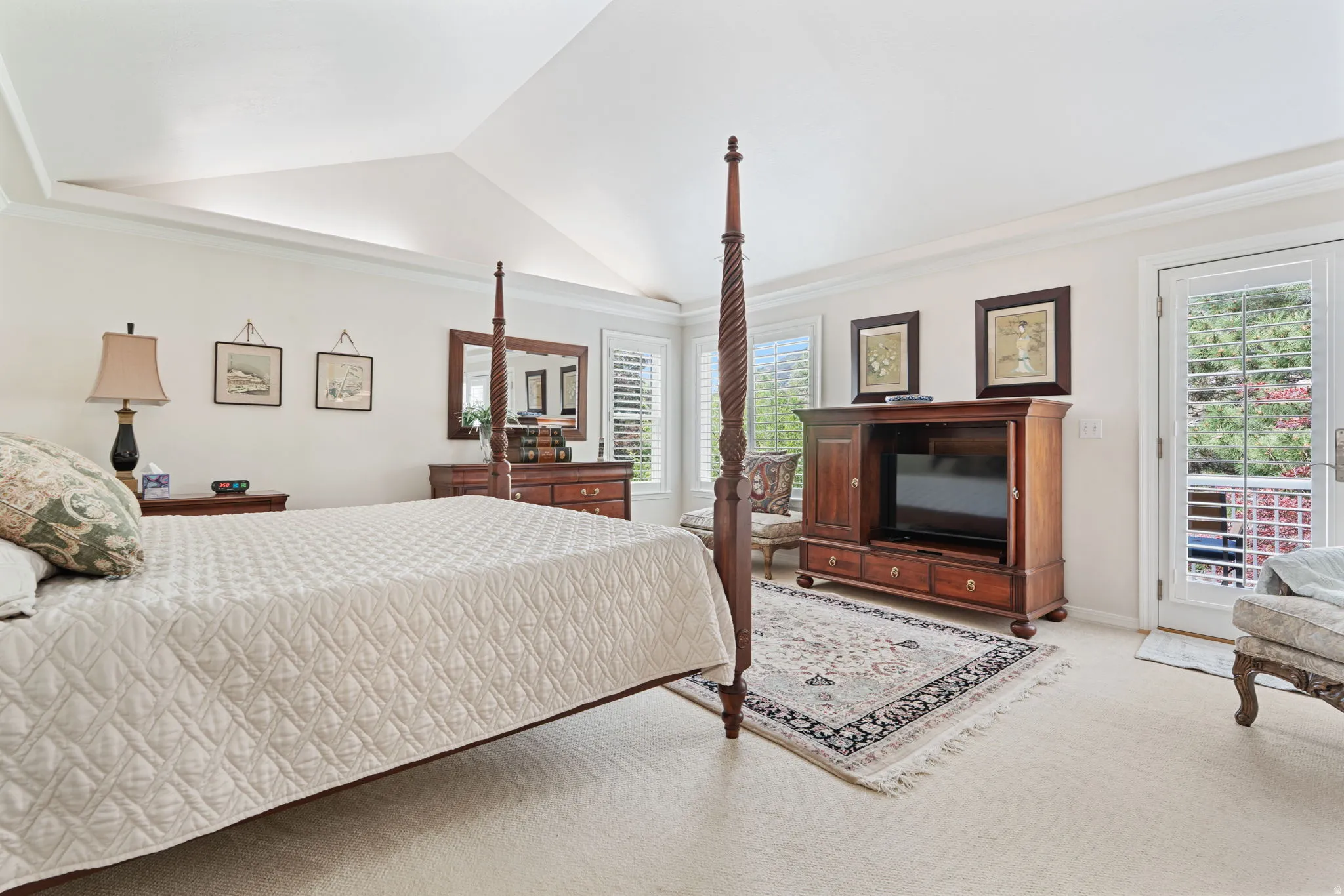 Vaulted ceiling featuring a central light fixture, carpeted flooring, white plantation shutters, and a glass-paned door