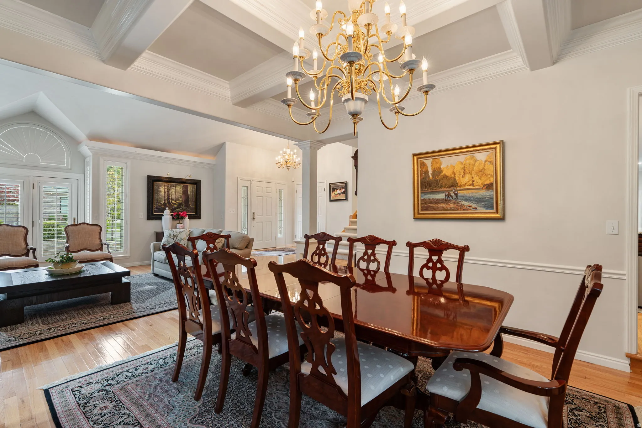 Formal dining area featuring a prominent chandelier, coffered ceilings, and wood-finish flooring