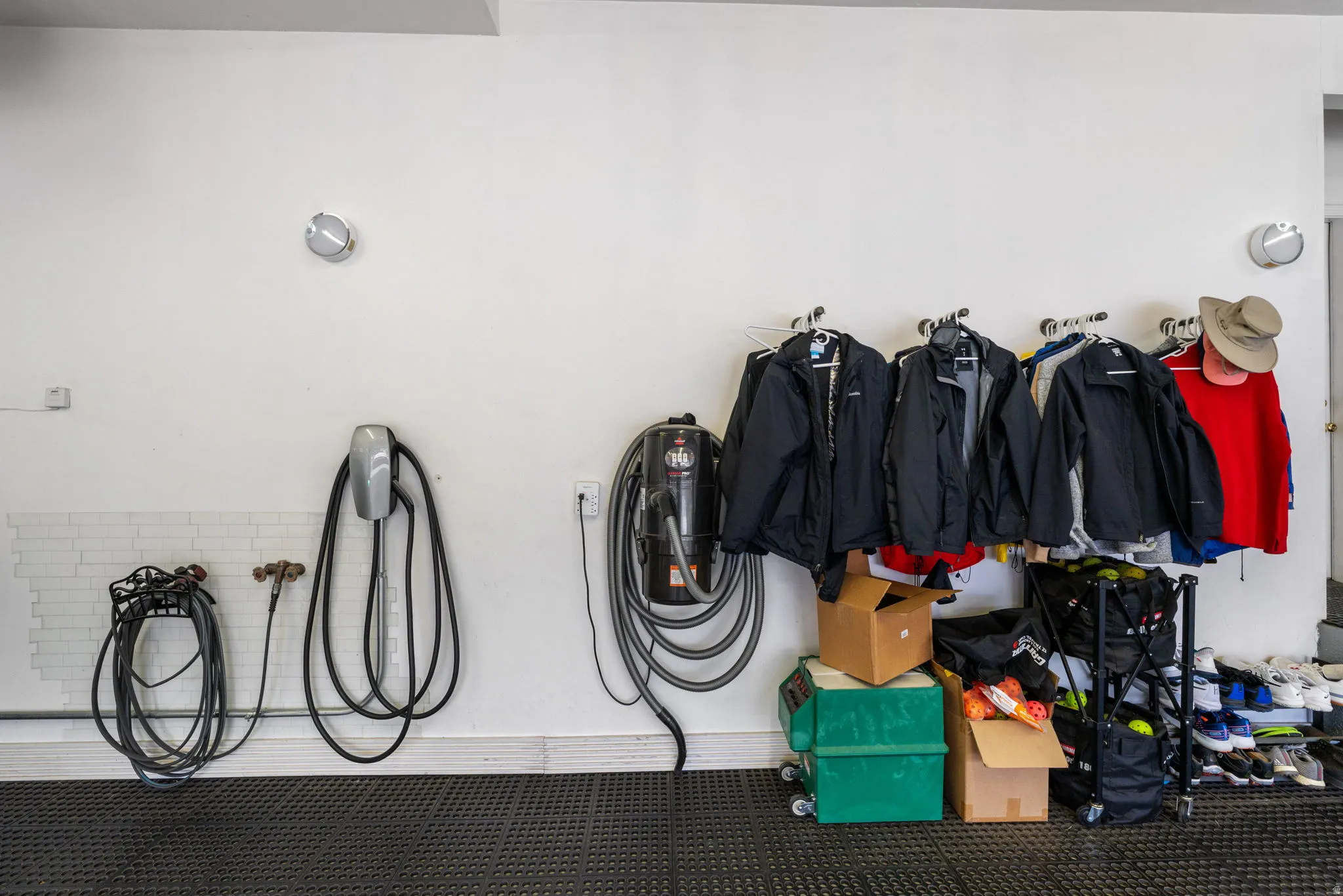 Expansive wall mounted heated garage space with epoxy floors covered with rubber tiles, EV charging station and wall vacuum