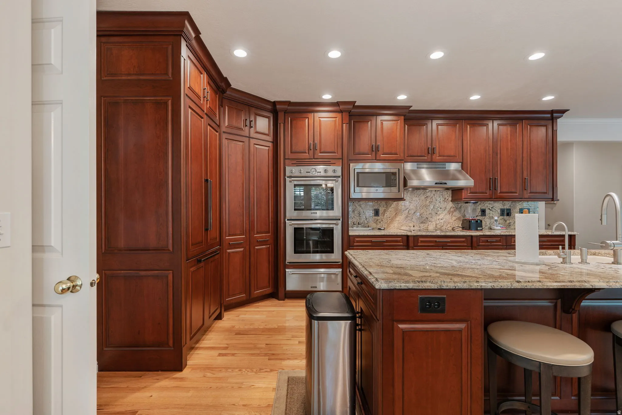 Mahogany wood cabinetry featuring an integrated refrigerator and Thermador double wall ovens