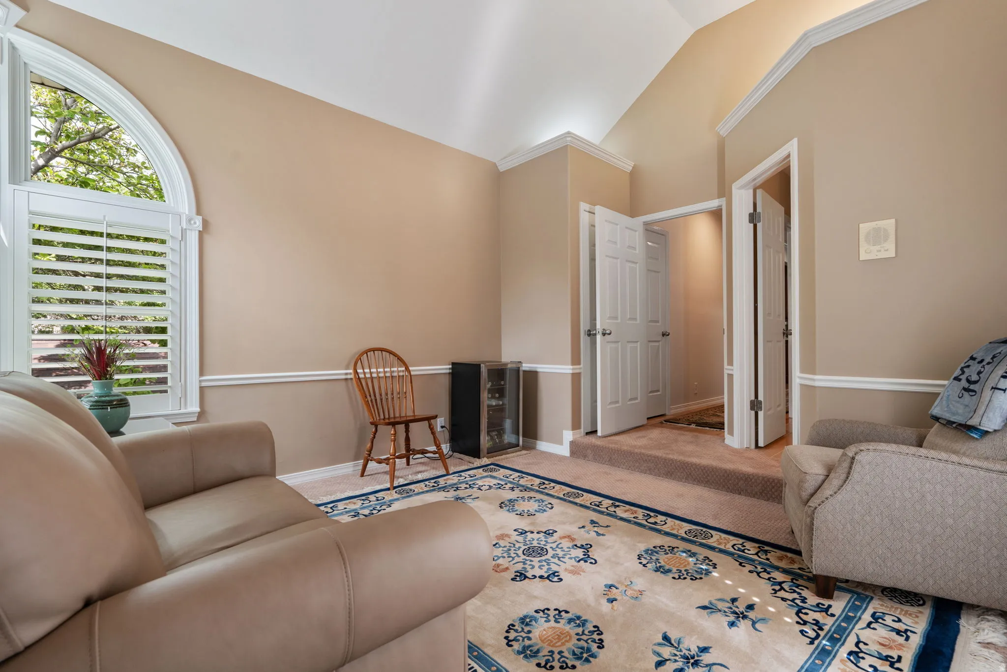 Guest suite with bathroom featuring an arched window with plantation shutters, vaulted ceiling, crown molding, and two-panel interior doors