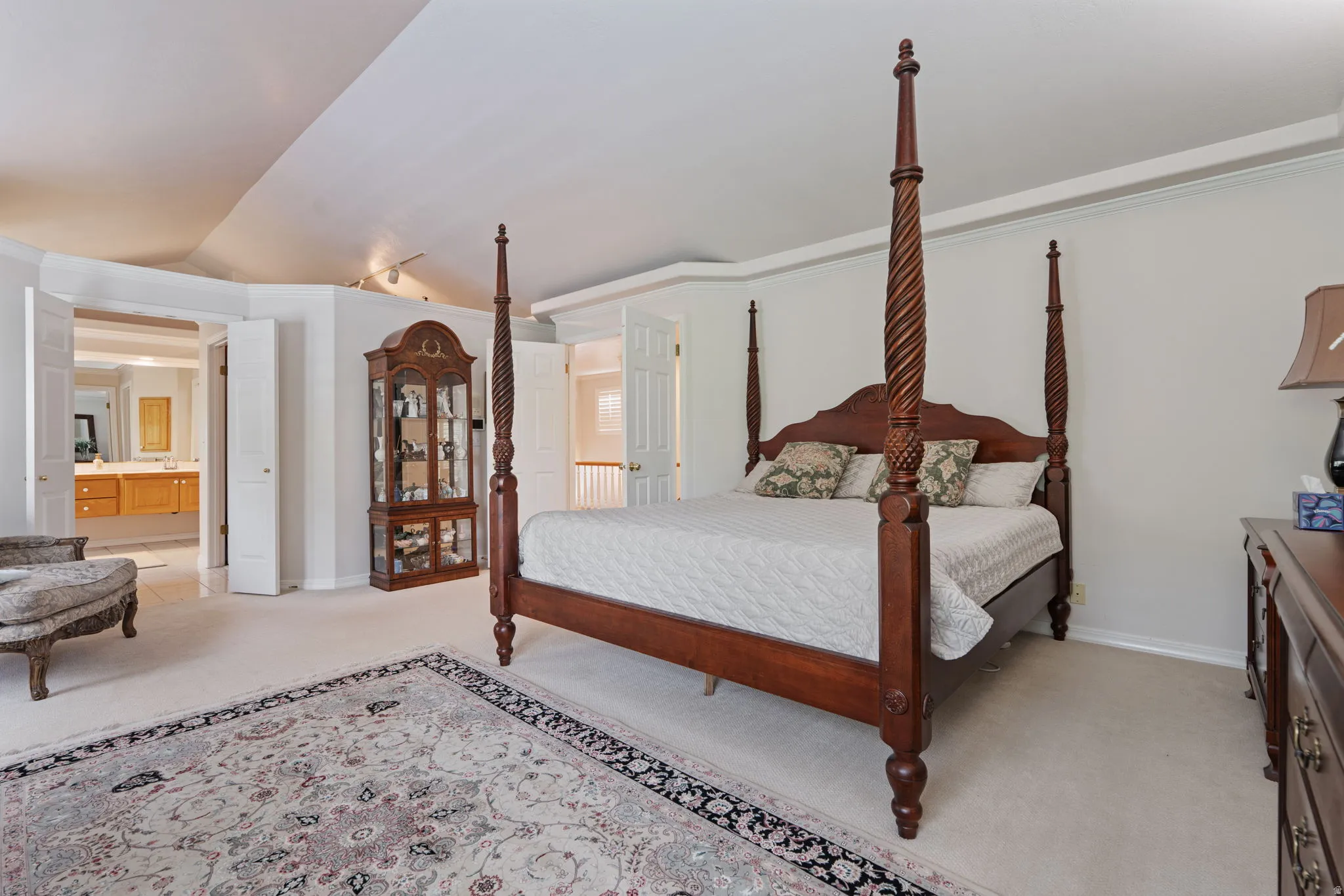 Spacious bedroom featuring plush carpeting, a vaulted ceiling, and crown molding